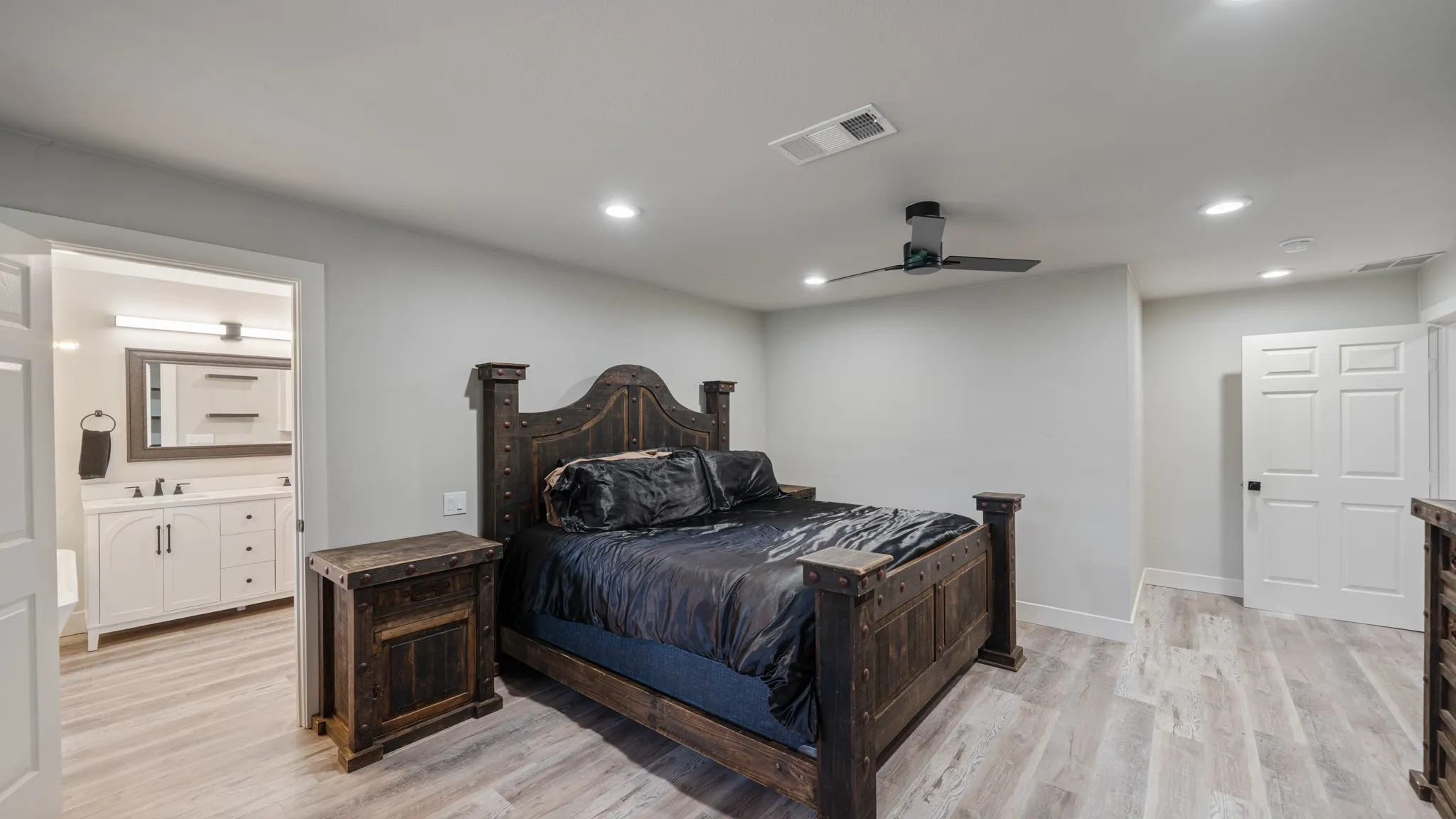 This bedroom features light-colored flooring, recessed lighting, and a ceiling fan