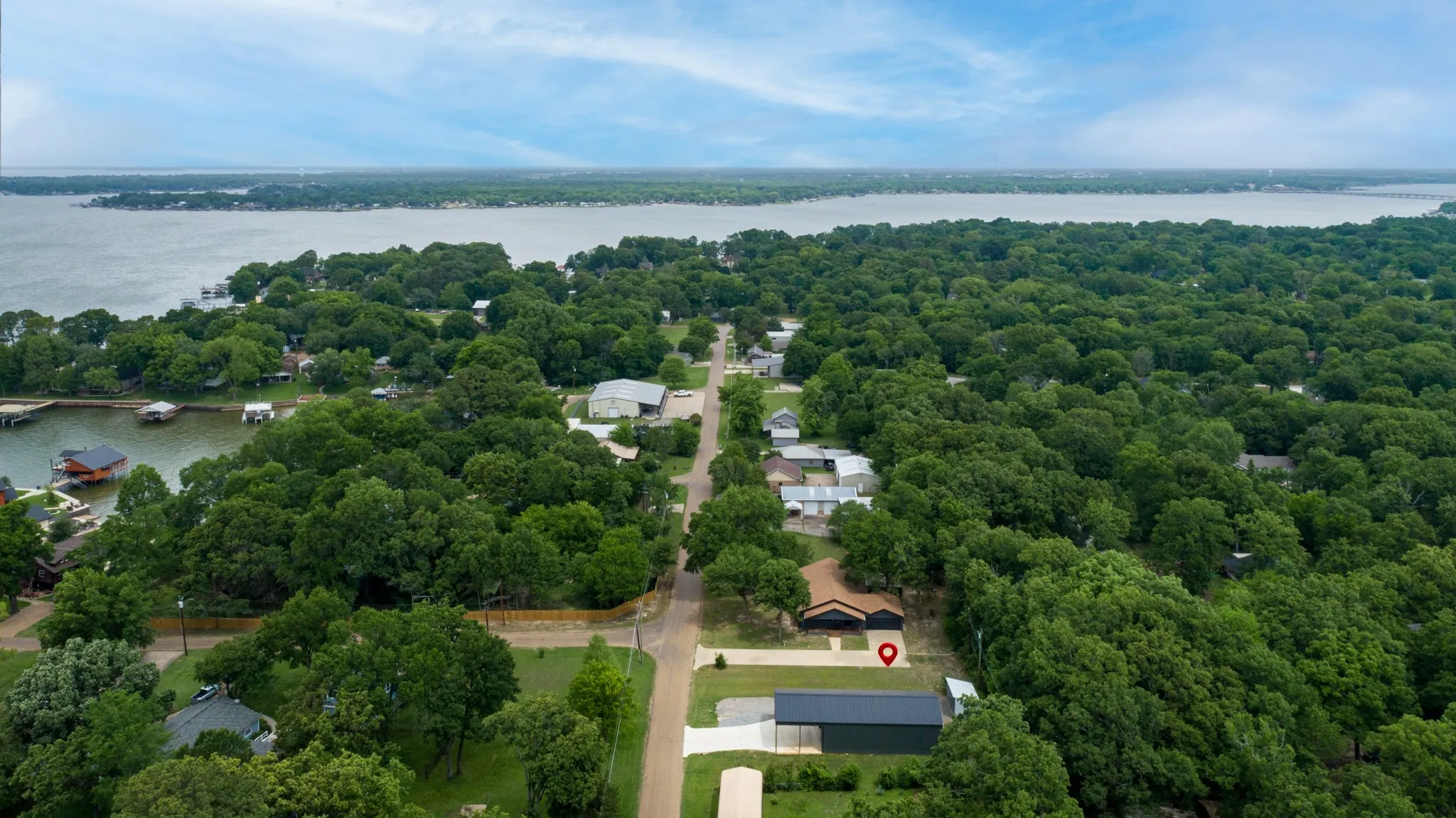 Aerial view showcasing the property's proximity to a large body of water, surrounded by lush green trees