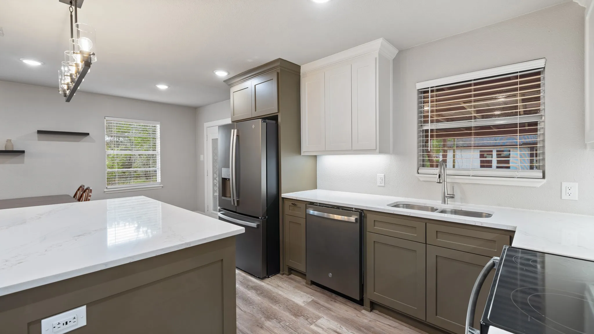 The kitchen features an island with a light-colored countertop, stainless steel appliances, and a double basin sink