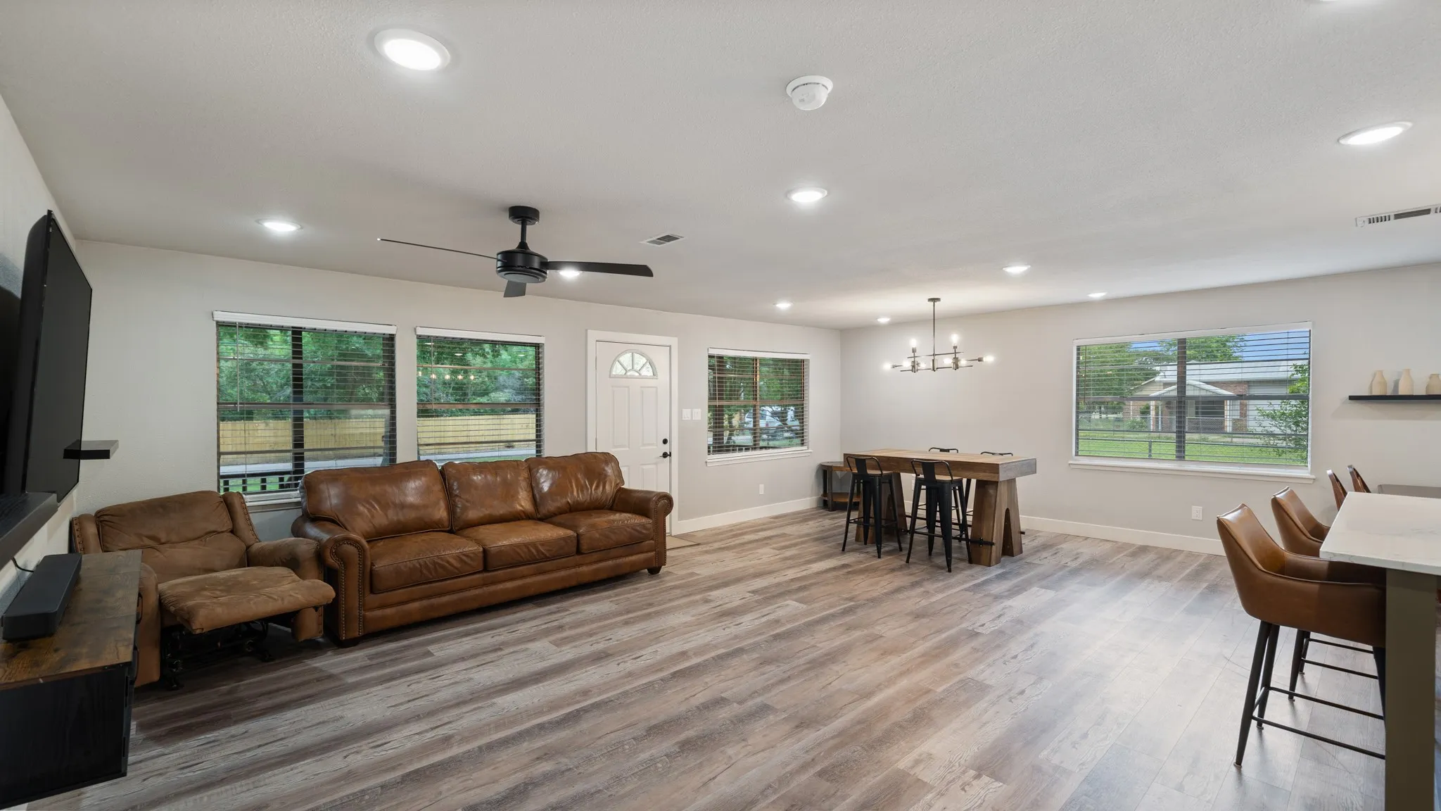 The living area features recessed lighting, light-colored walls, and wood-look flooring