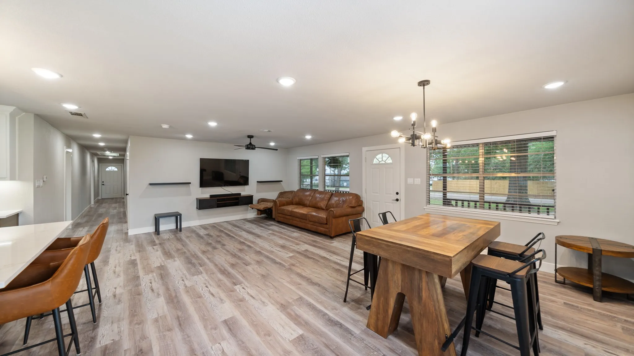 Spacious living area featuring light-toned flooring, recessed lighting, and a modern chandelier