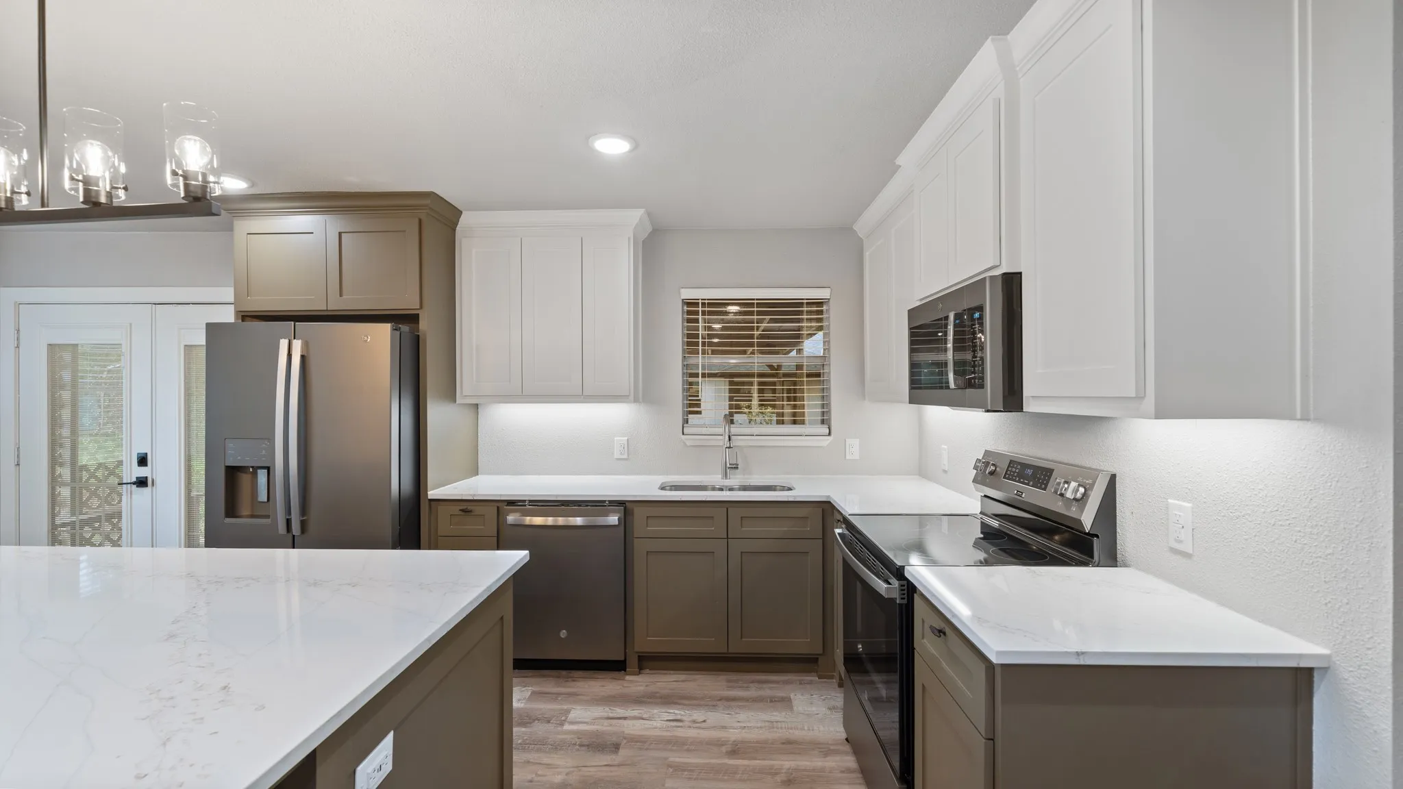 Modern kitchen featuring white and grey cabinetry, stainless steel appliances, white countertops, and wood-style flooring