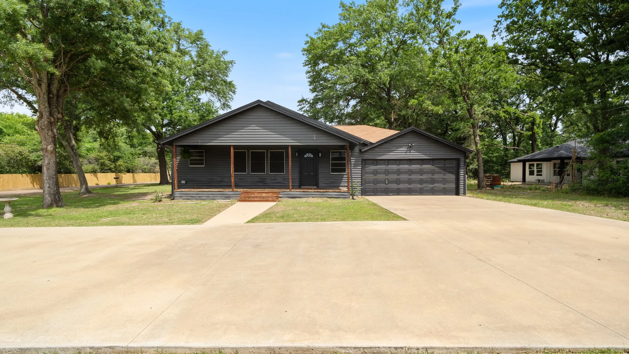 Property exterior featuring dark gray siding, a covered porch with wooden posts, and an attached two-car garage