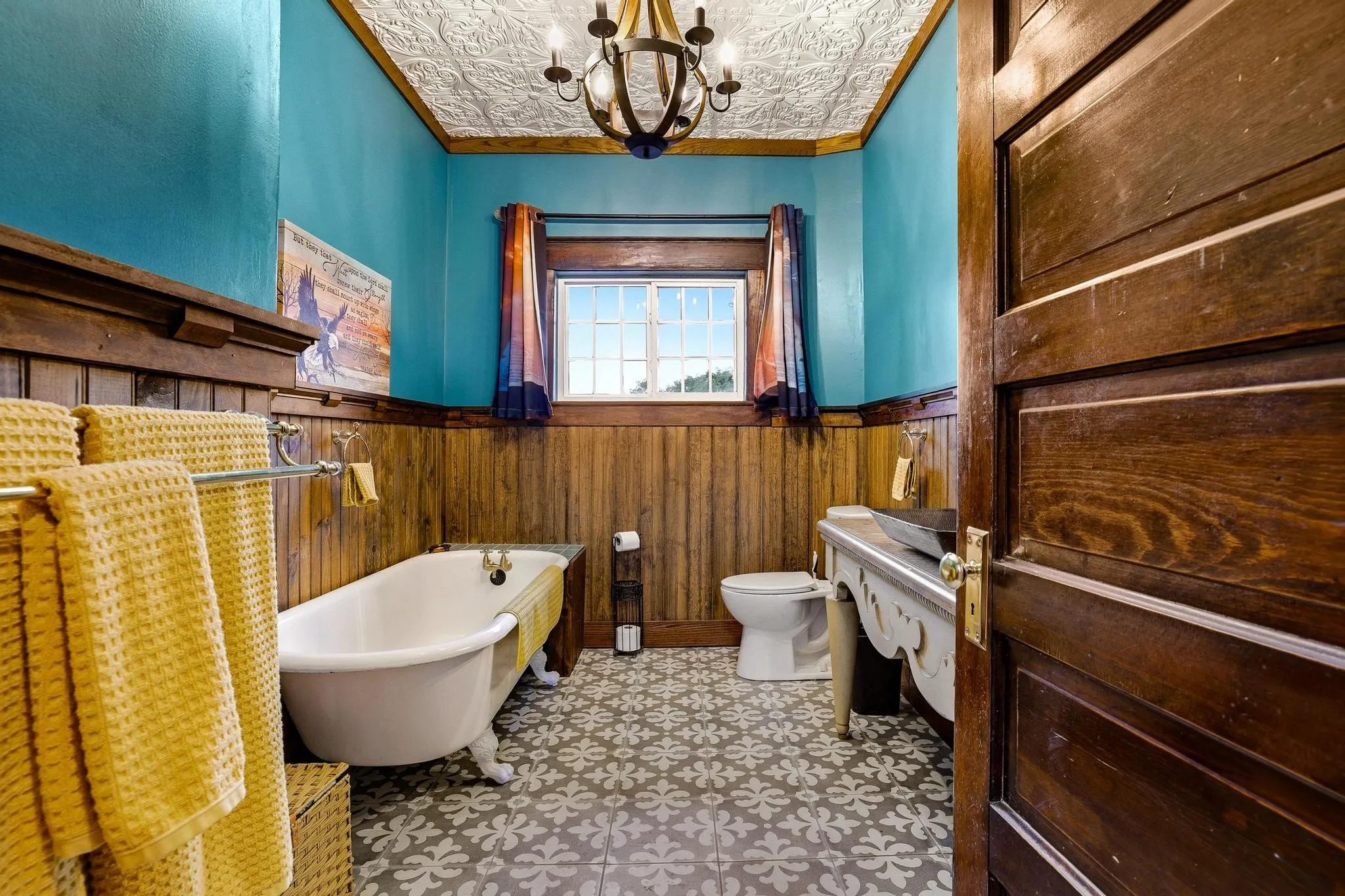 Bathroom featuring a freestanding clawfoot tub, patterned floor tiles, and wood paneling on the lower walls