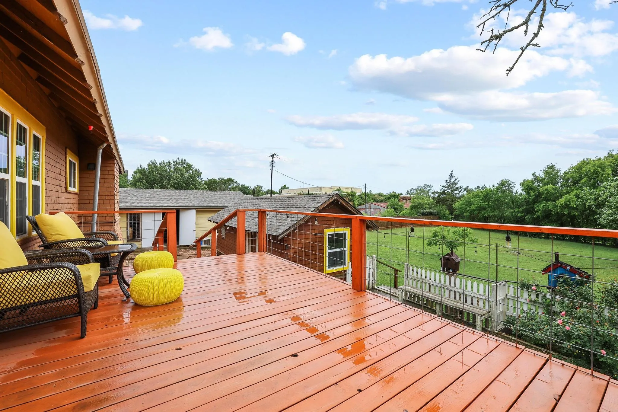 Expansive outdoor deck with a sturdy railing, providing views of a fenced-in yard and distant greenery