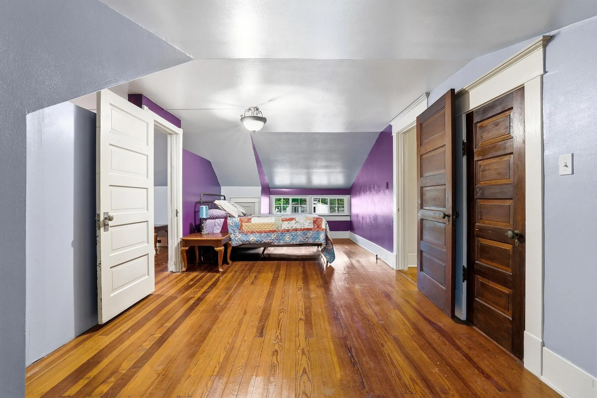 This spacious room features hardwood flooring, a ceiling-mounted light fixture, and windows that provide natural light