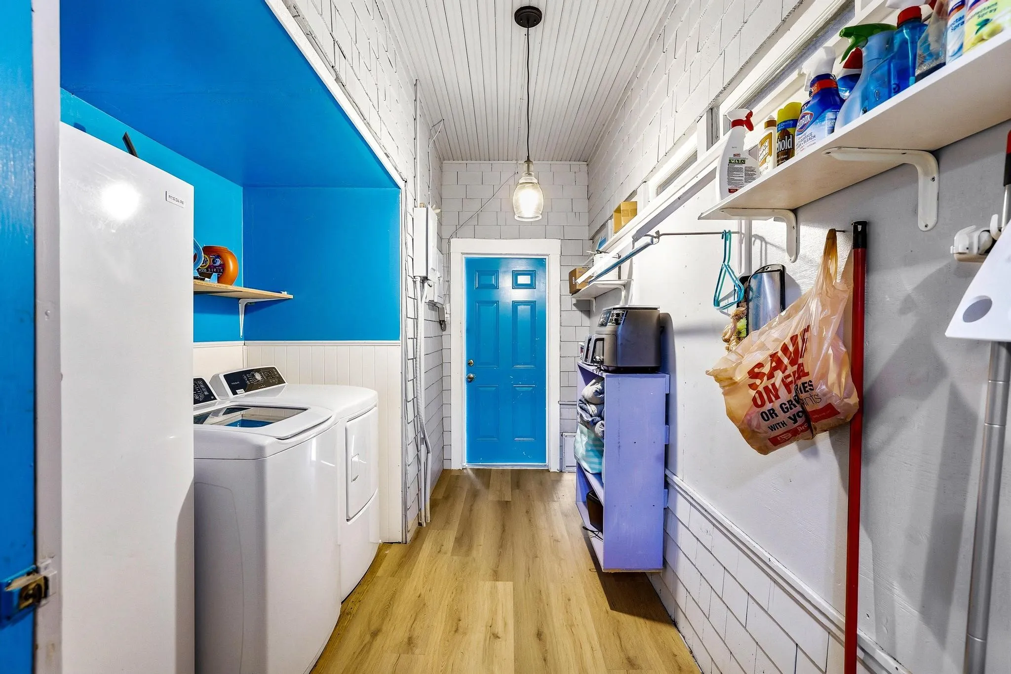 This utility space features a wood plank floor and white beadboard wall paneling