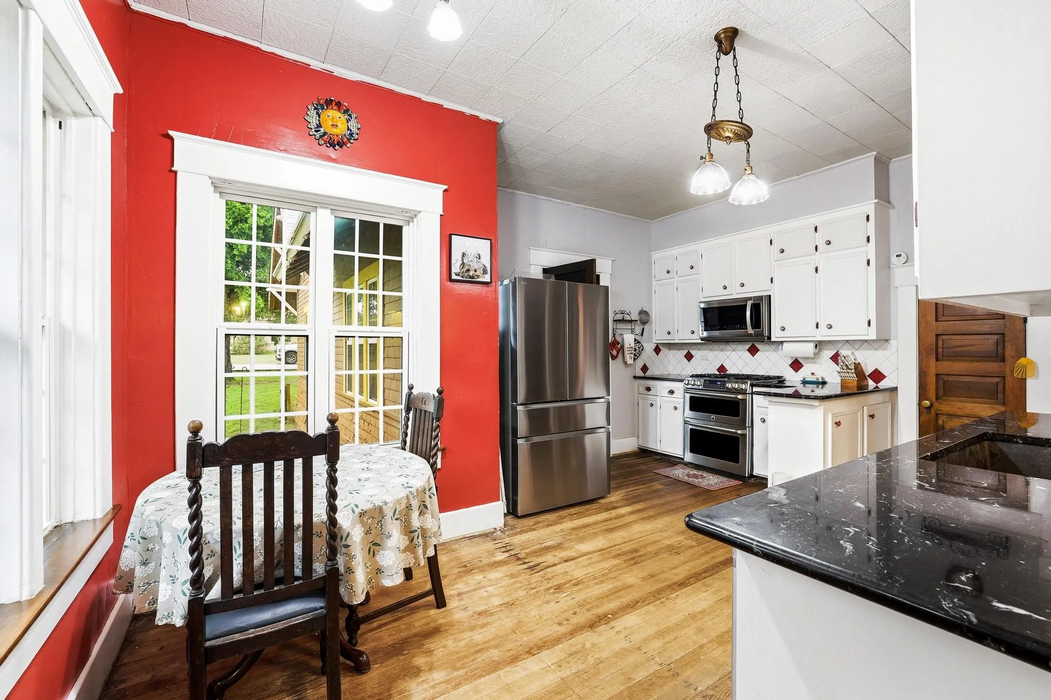 The kitchen features hardwood floors, white cabinetry, and stainless steel appliances