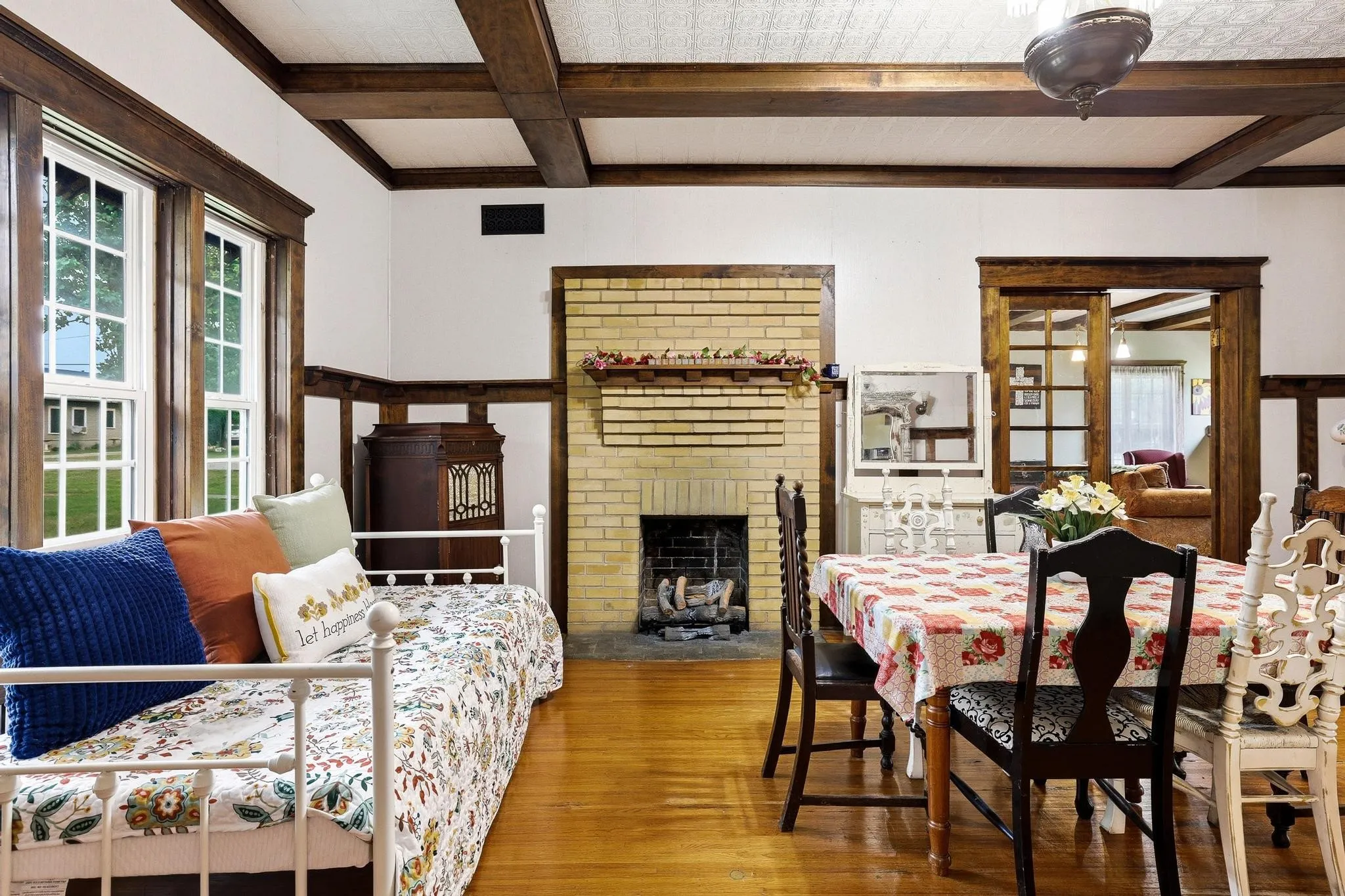 The interior features wood flooring and exposed wood beams on the ceiling, complemented by a brick fireplace