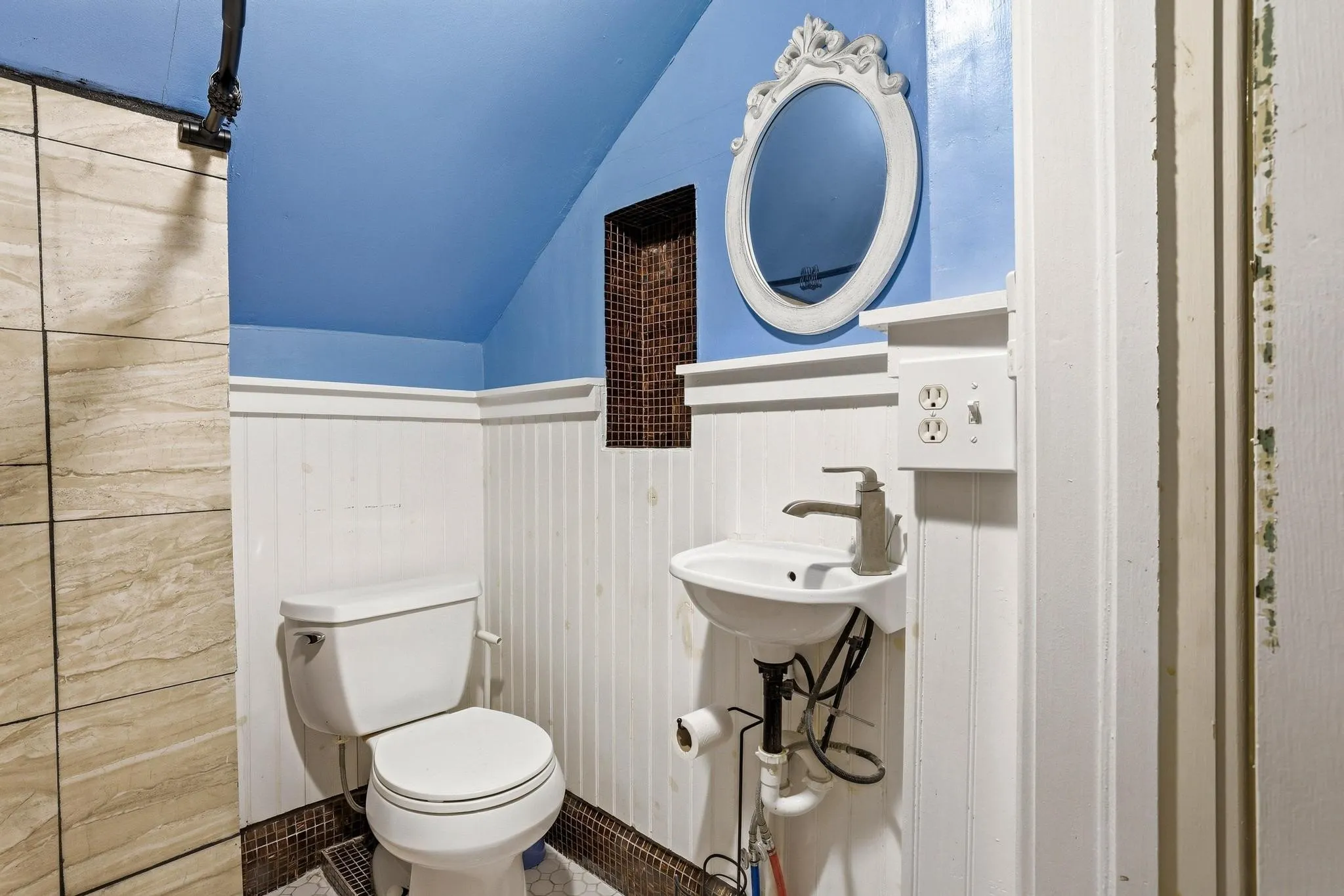 Bathroom featuring a toilet, a pedestal sink with a faucet, and an ornate mirror