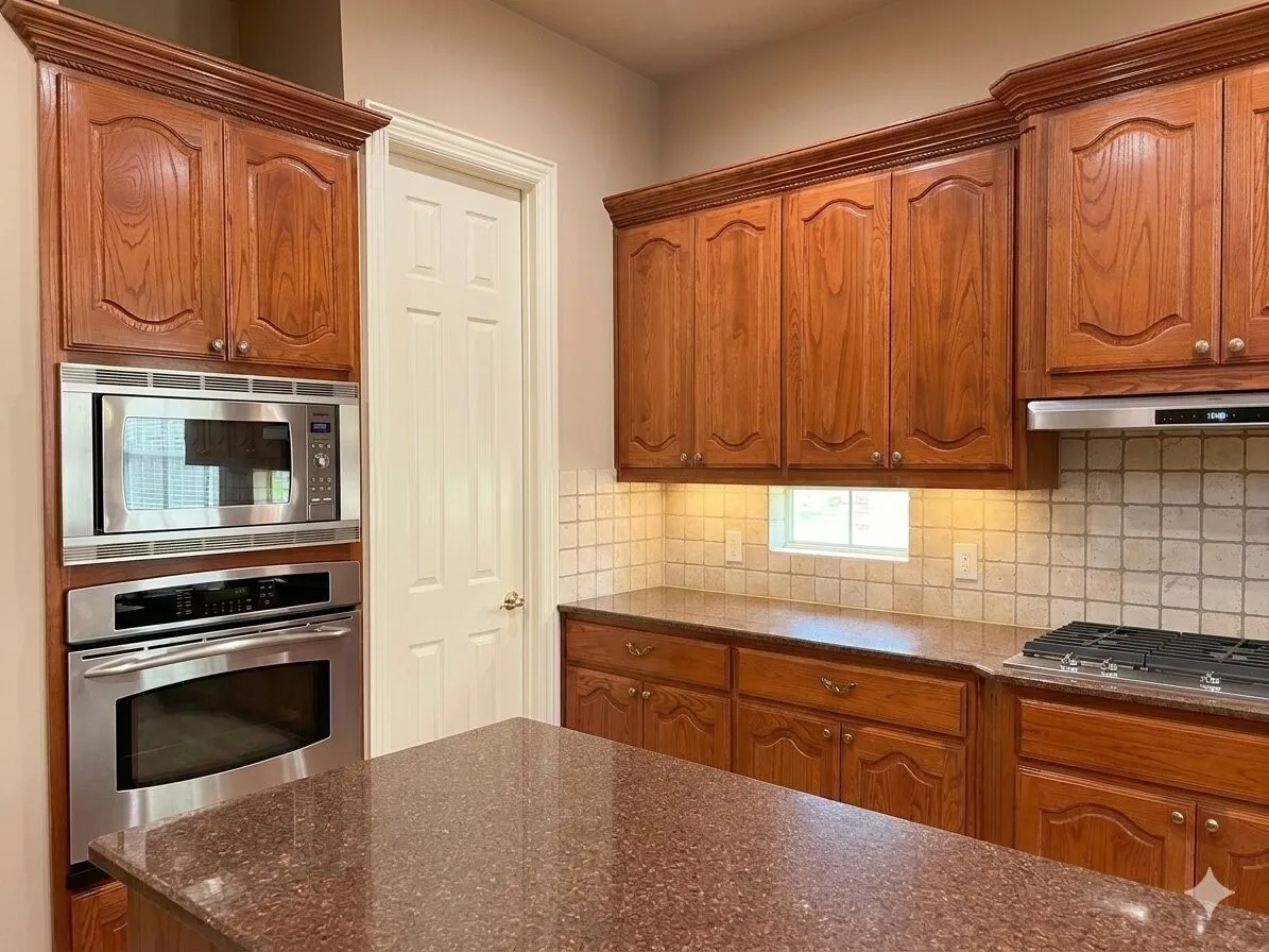 Kitchen featuring rich wood cabinetry with decorative molding, stainless steel built-in microwave and oven, a built-in gas cooktop, tiled backsplash, and stone-finish countertops