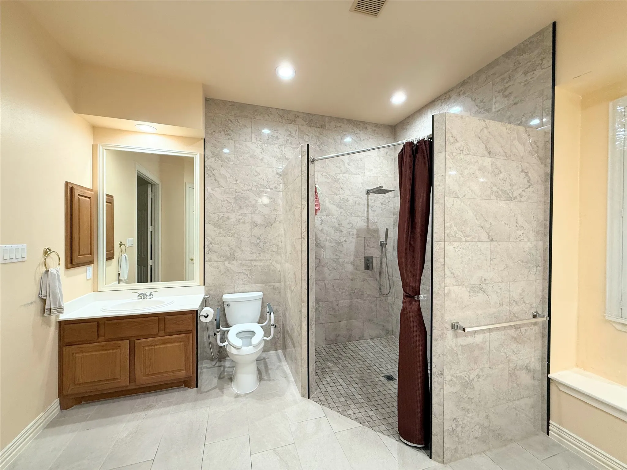 Spacious bathroom featuring a large walk-in shower with tiled walls and a rain showerhead