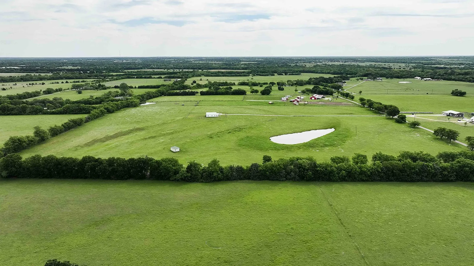 Expansive green landscape featuring a natural pond and extensive tree lines