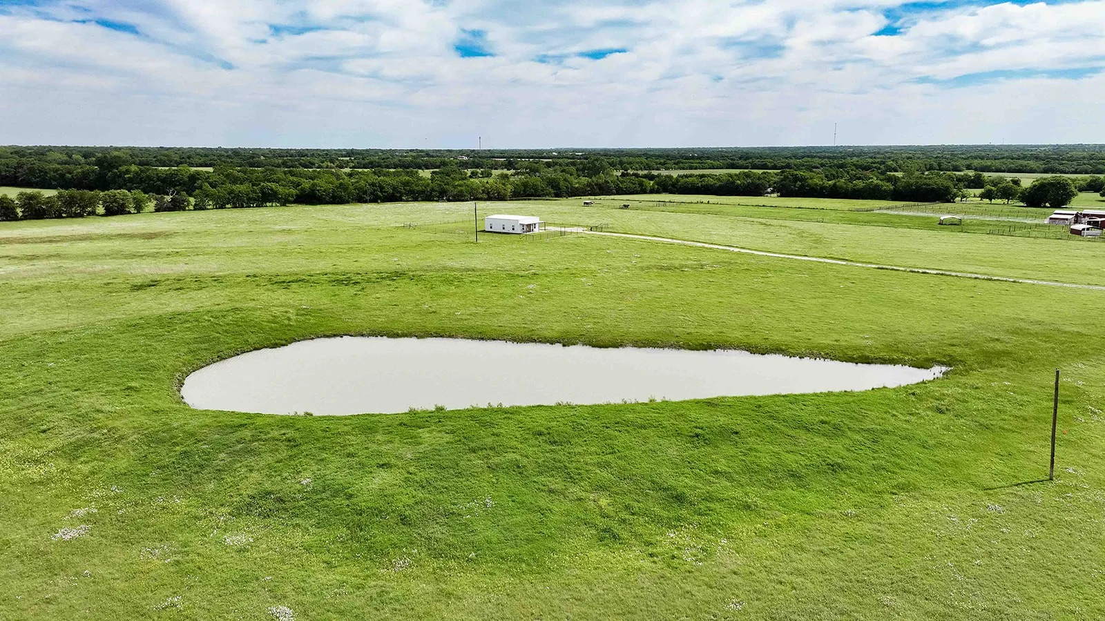 Expansive green pastureland featuring a prominent pond
