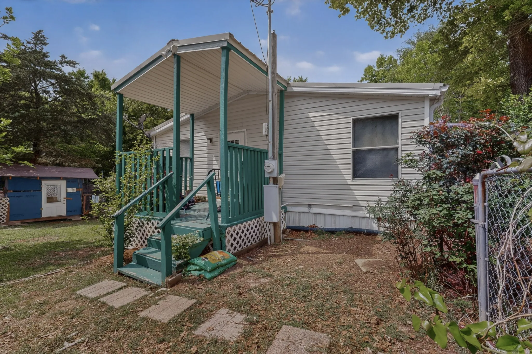 The property features a covered porch with green railings and steps, and light-colored siding