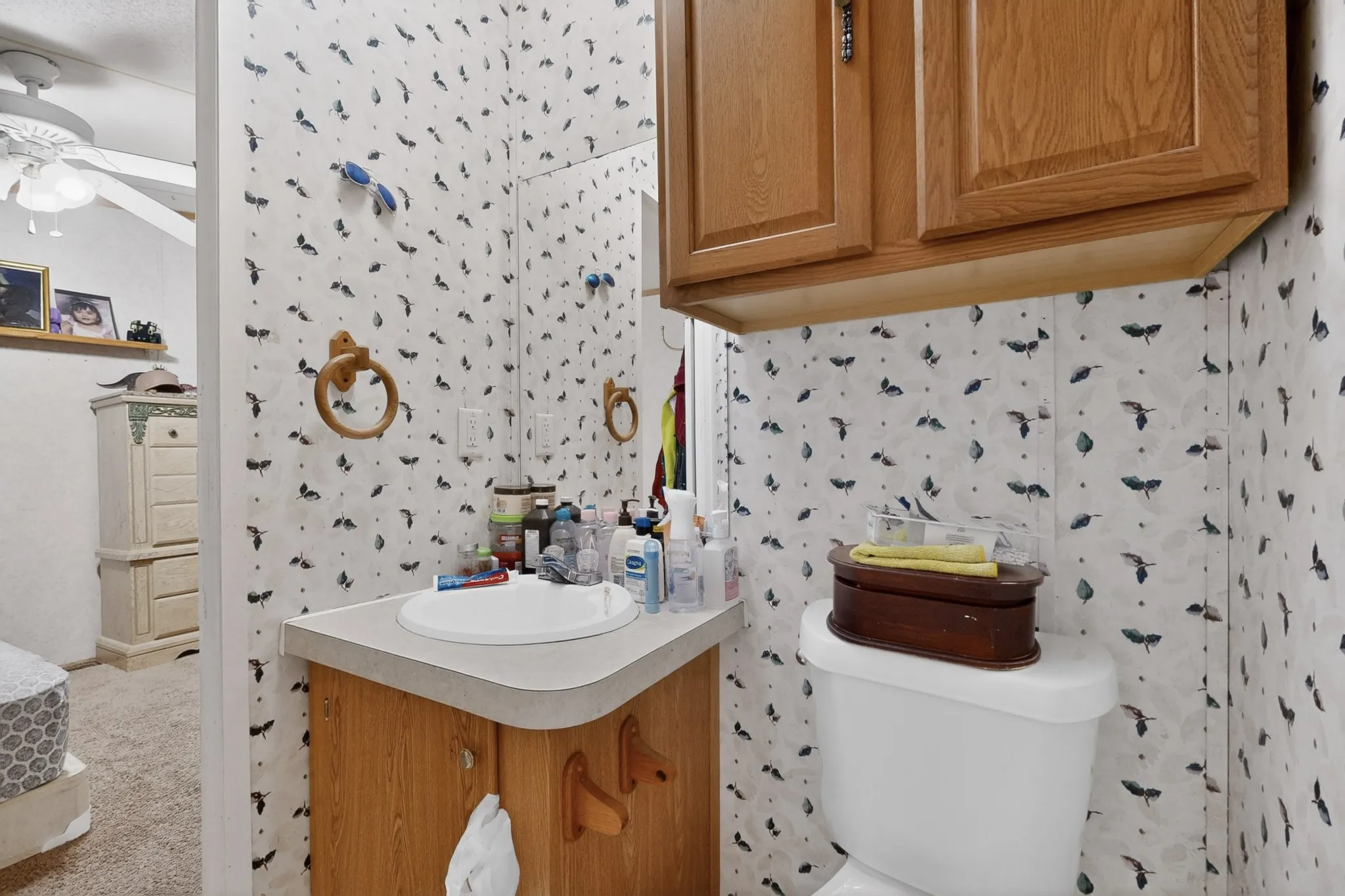 Bathroom featuring a vanity with an integrated sink and light wood cabinetry, a toilet, and wall-mounted wooden cabinets