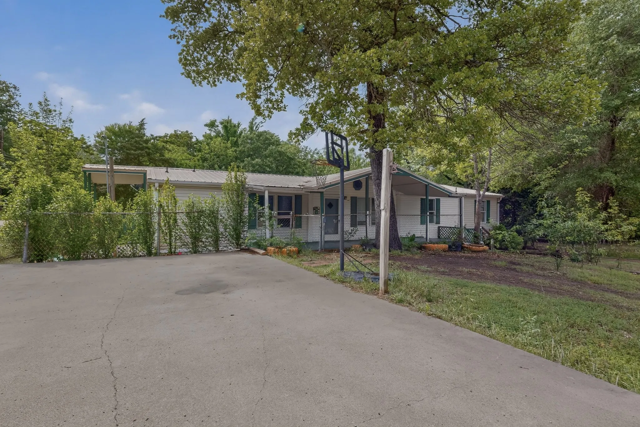 The property features a concrete driveway and mature trees
