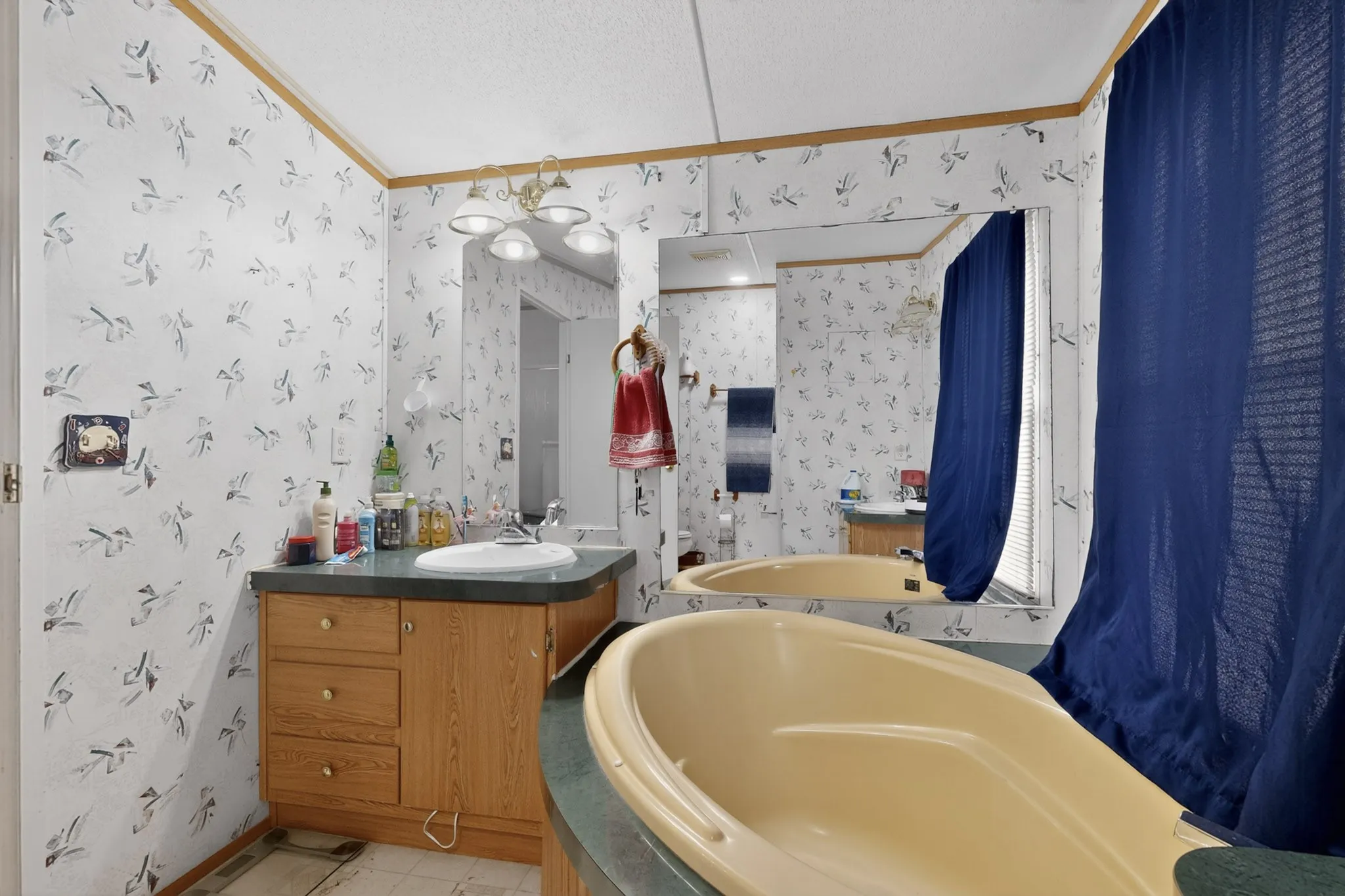The bathroom features a built-in tub, a vanity with a sink, and a large mirror