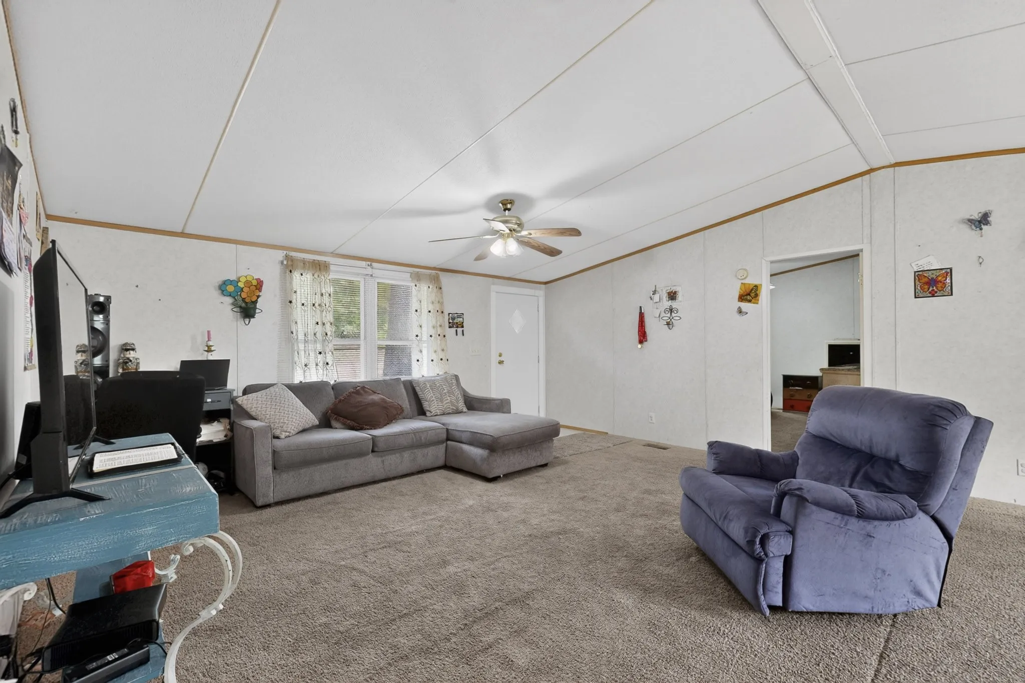 The property features a spacious living area with carpet flooring and a ceiling fan