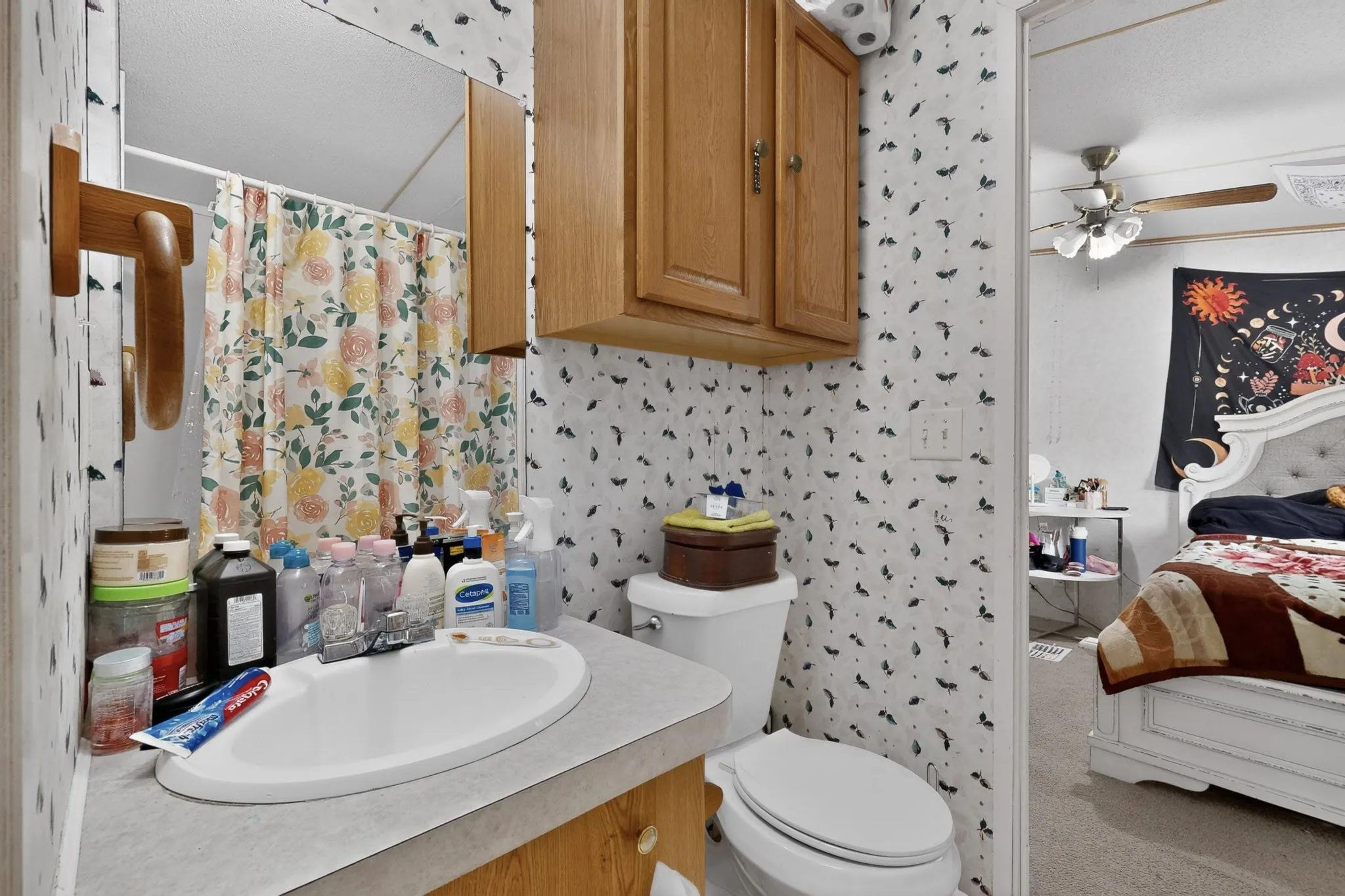 The property features a bathroom with a toilet, a vanity with an integrated sink, and an overhead wooden cabinet