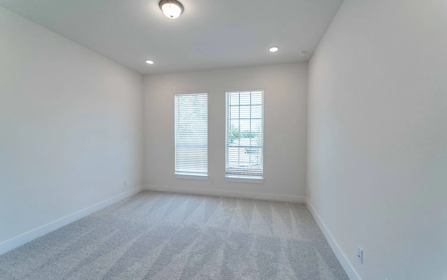 Room with plush carpet flooring, two large windows with blinds, recessed lighting, and a flush mount ceiling fixture