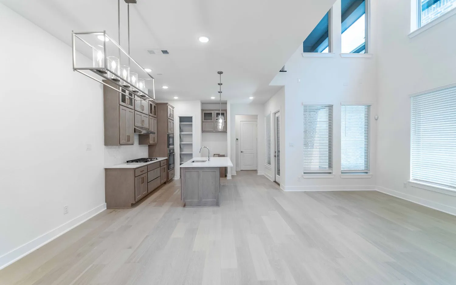 Open-concept living area featuring a kitchen with shaker-style cabinetry, a central island with a sink, and stainless steel appliances