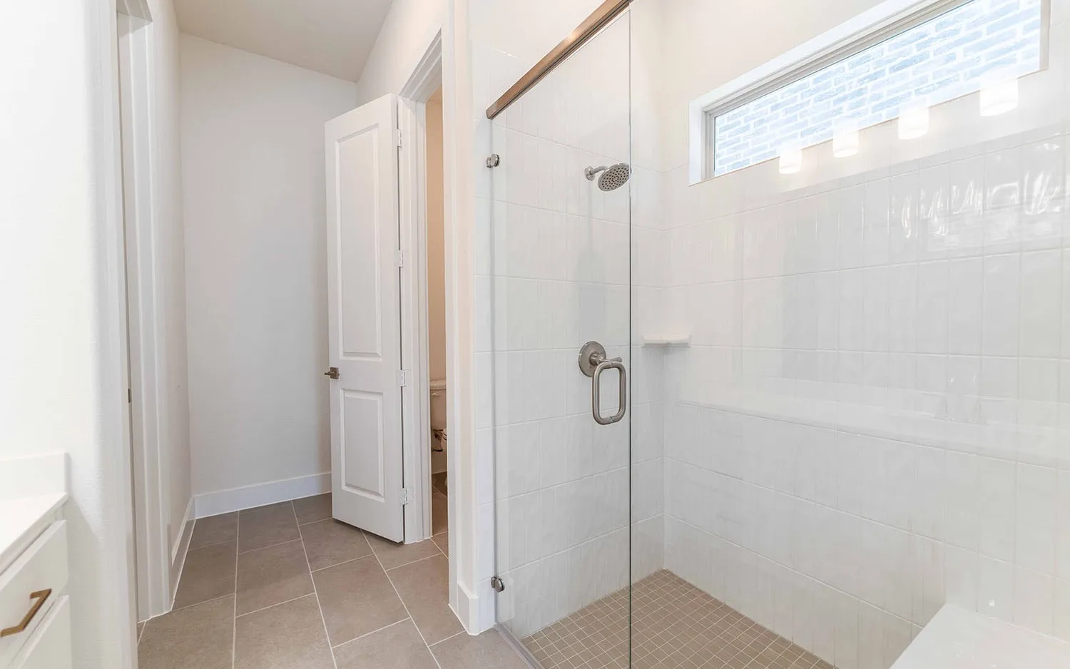 Spacious shower with a glass enclosure, rain showerhead, and built-in bench