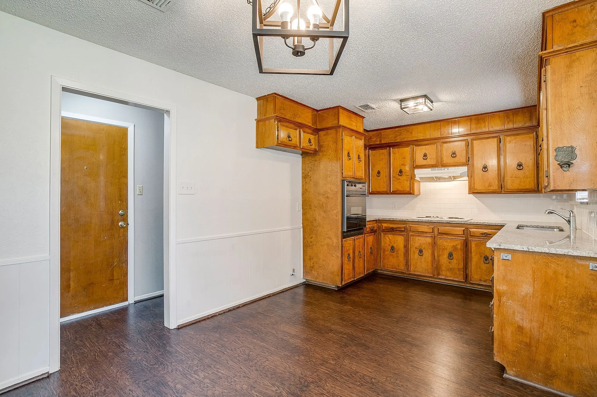 The kitchen features extensive wooden cabinetry, a built-in oven, and a sink with a countertop