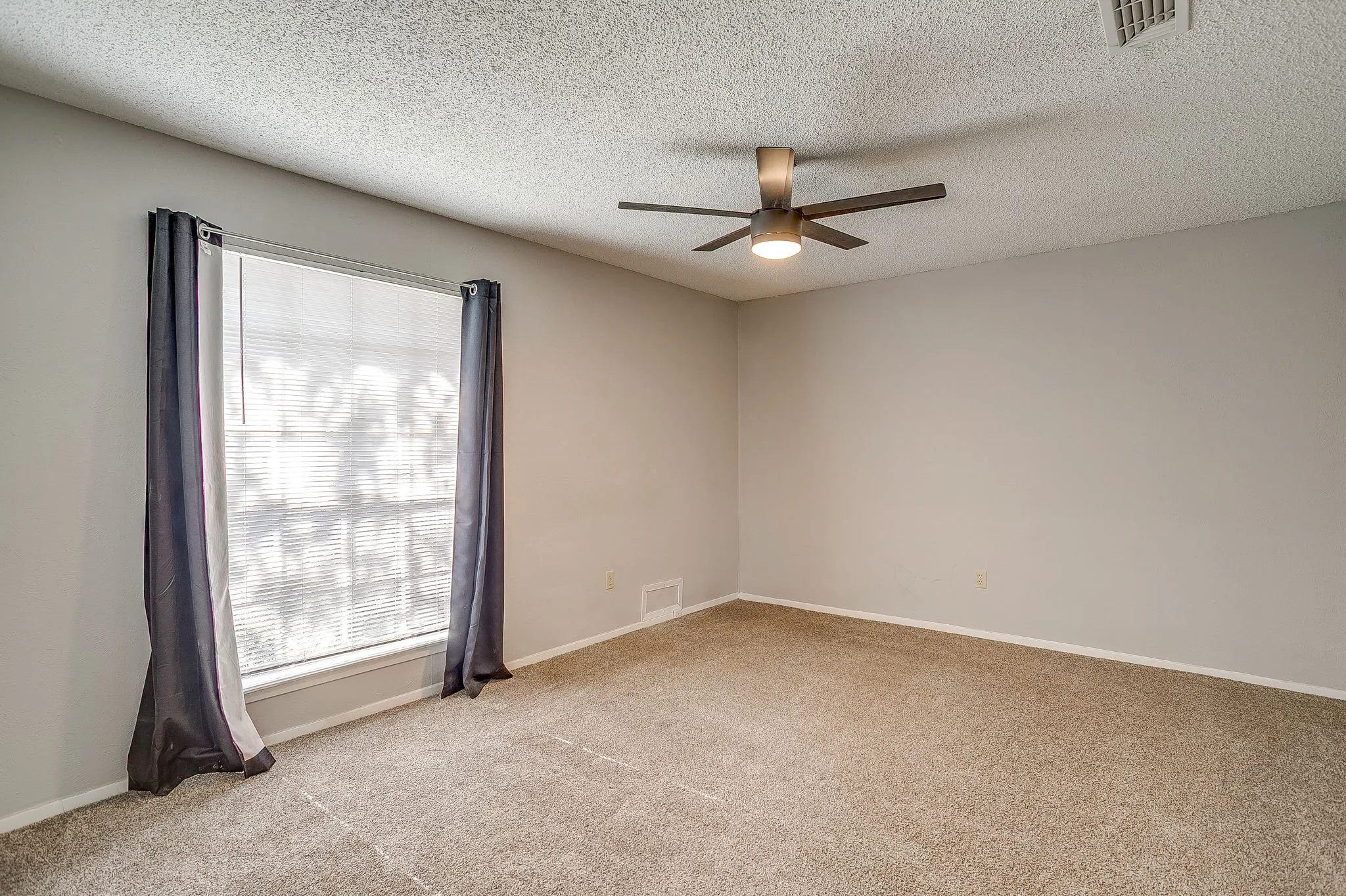 This room features a window with blinds, carpeted flooring, and a ceiling fan with integrated lighting