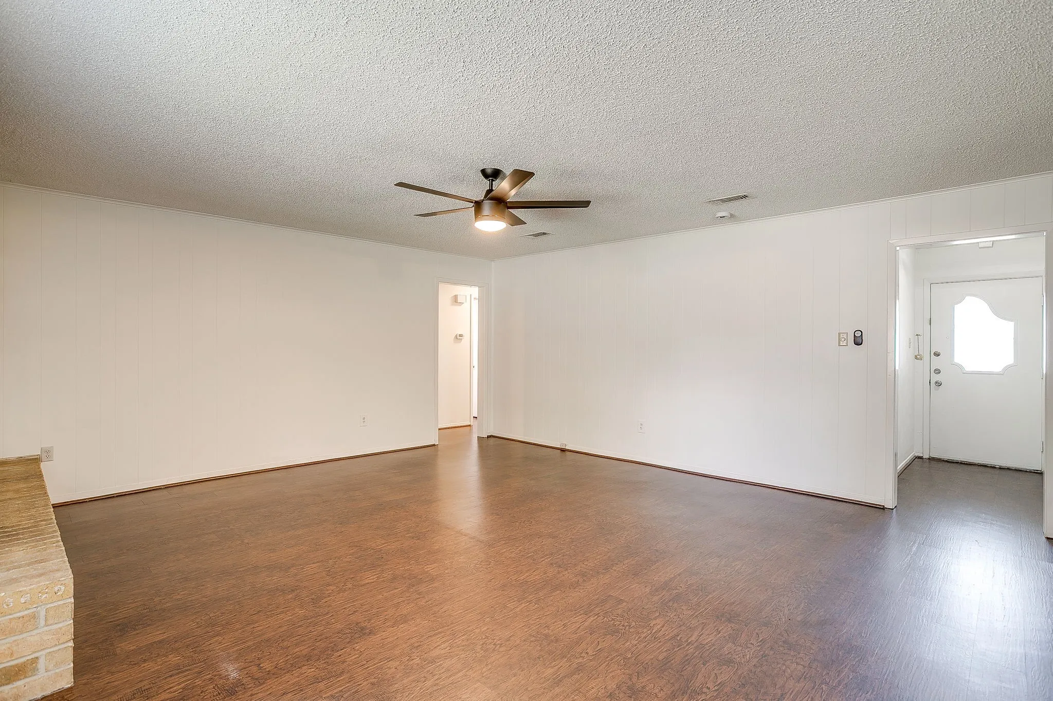 The property features wood-look flooring, white walls, and a ceiling fan with integrated lighting