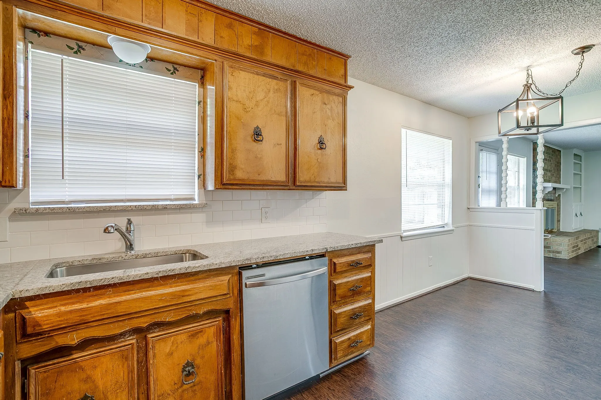 The kitchen features wood cabinetry, a stainless steel sink, and a stainless steel dishwasher