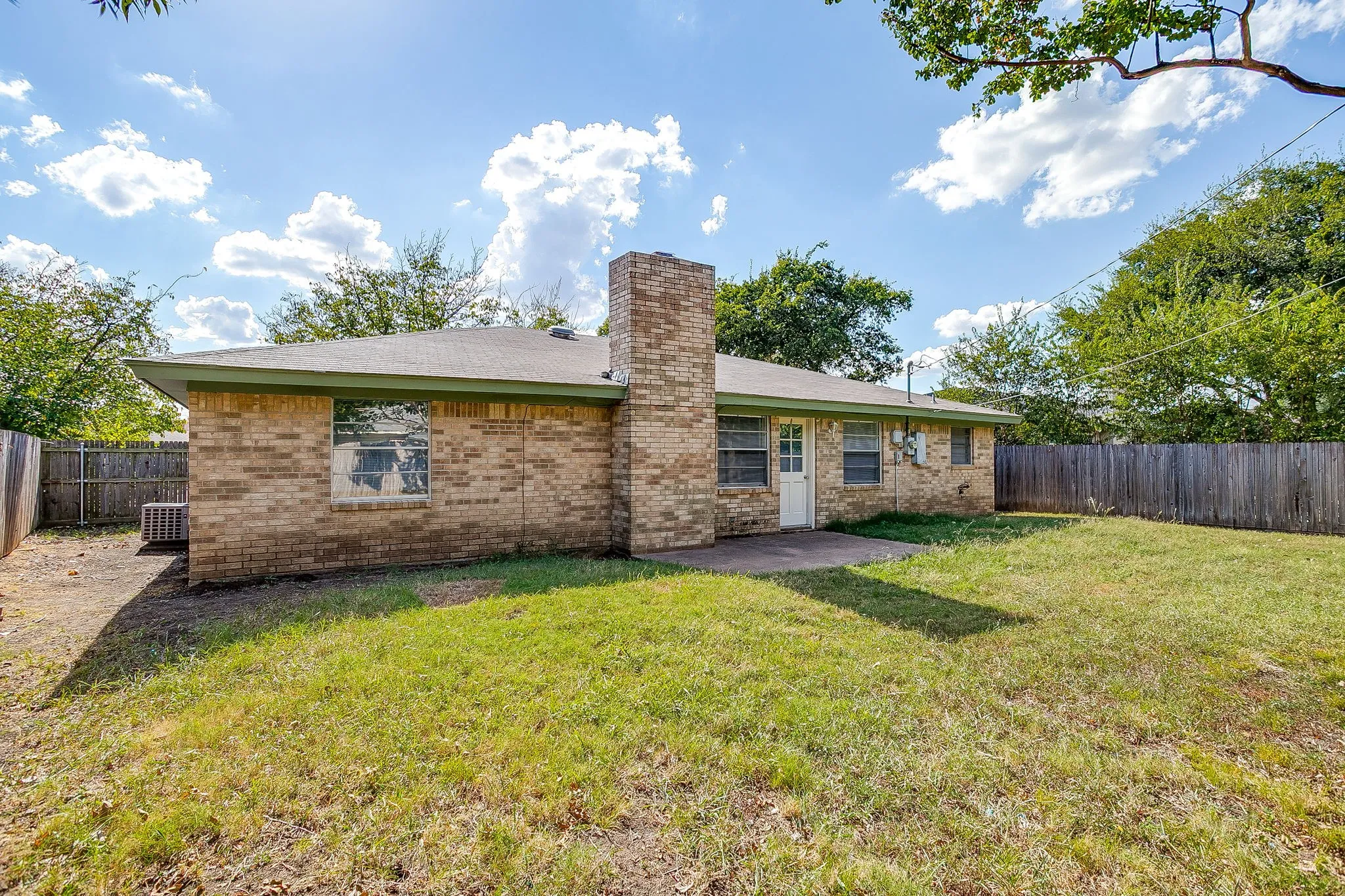 The property features a brick exterior, a substantial lawn area, and a private fenced yard