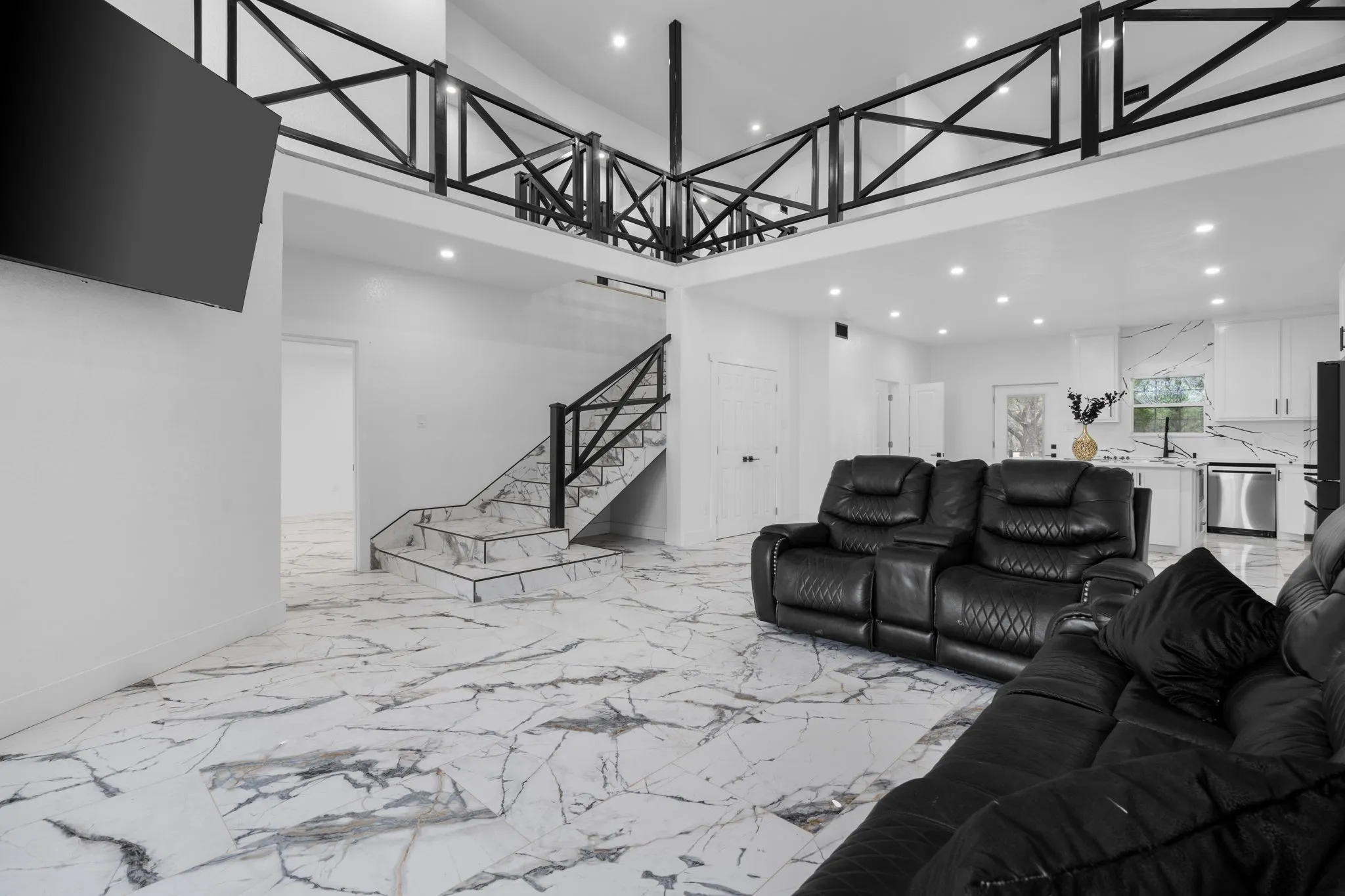 Open-concept interior featuring high ceilings and a second-level loft with decorative black railing