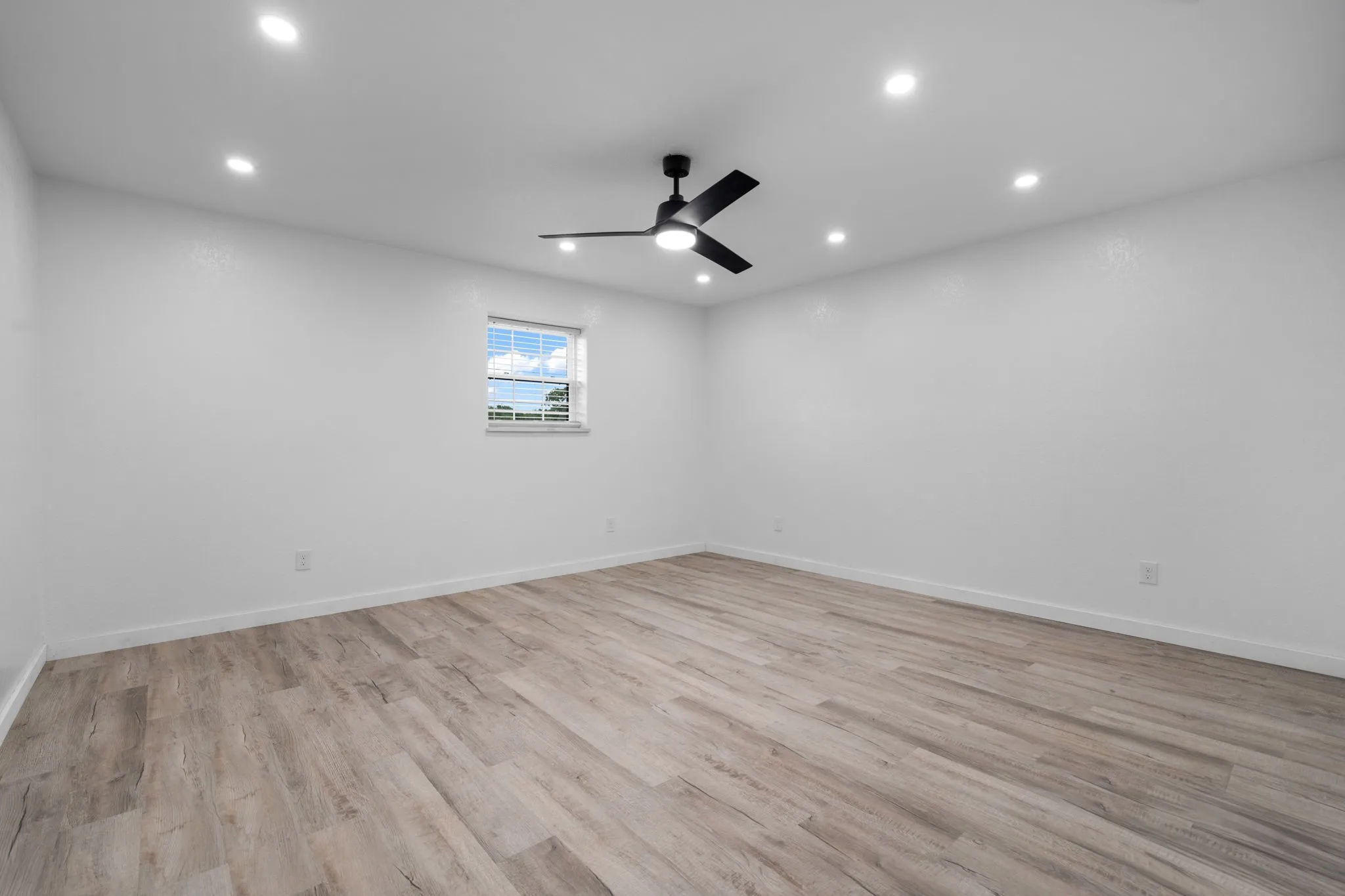 Guest bedroom Spacious room featuring wood-finish flooring, recessed lighting, and a modern ceiling fan