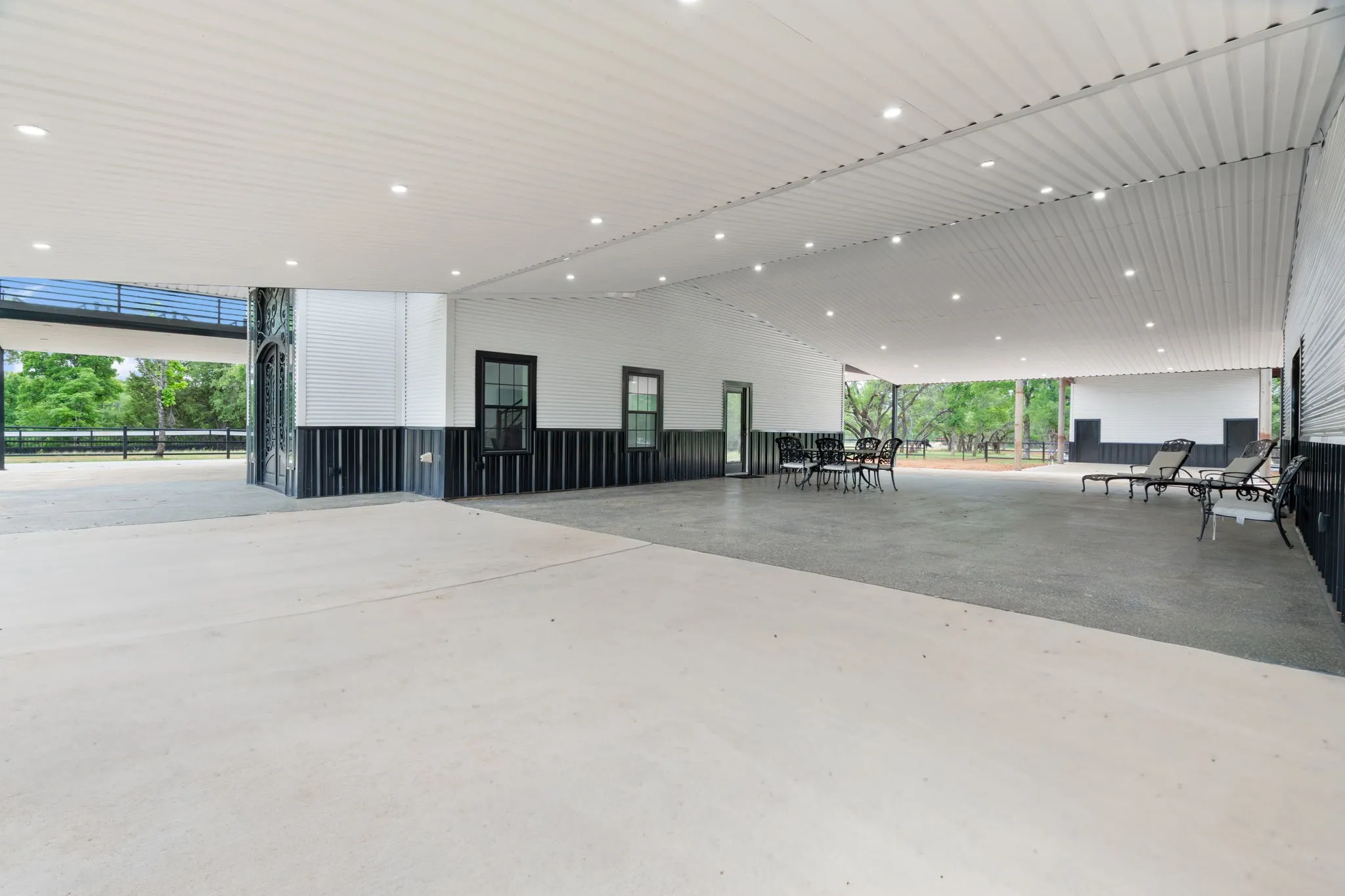 Expansive covered outdoor living area featuring a corrugated metal ceiling with recessed lighting