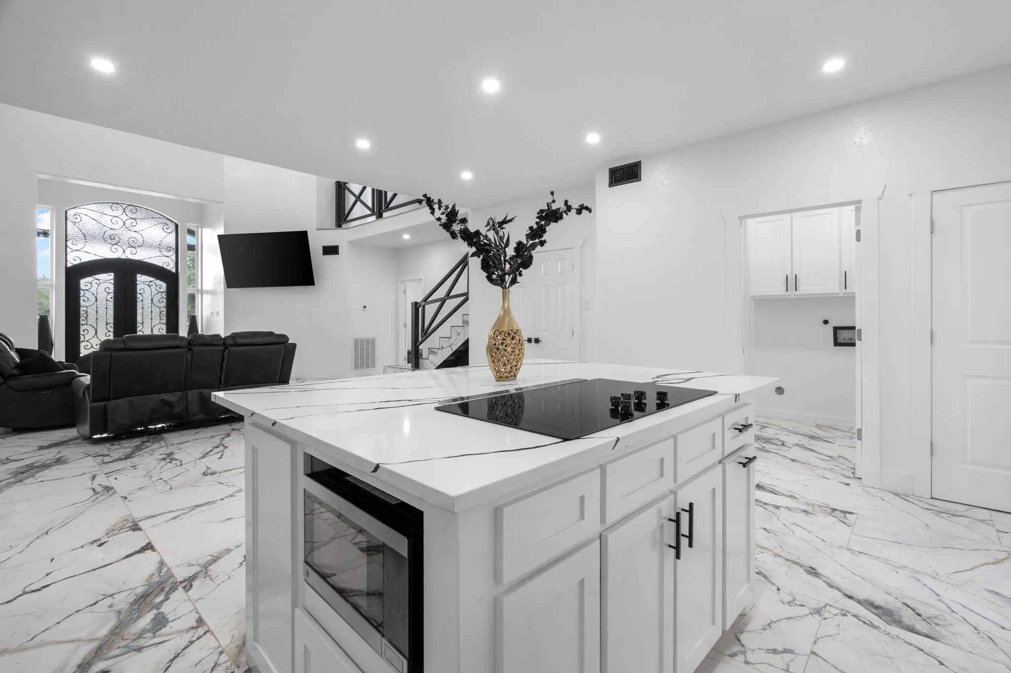 Kitchen island with built-in cooktop and microwave, featuring white cabinetry and a white countertop with grey veining