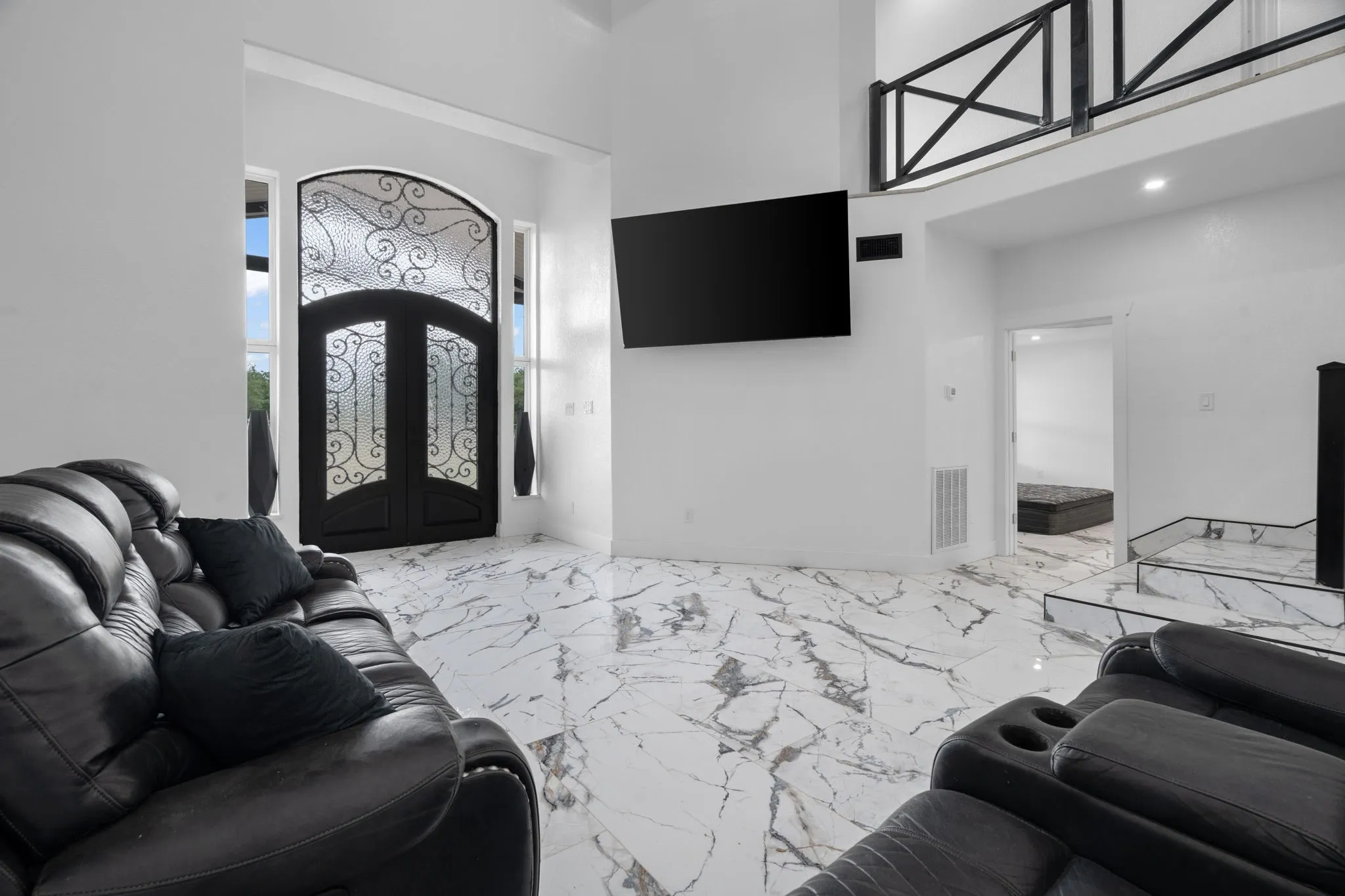 Grand entryway featuring double doors with decorative wrought iron and frosted glass