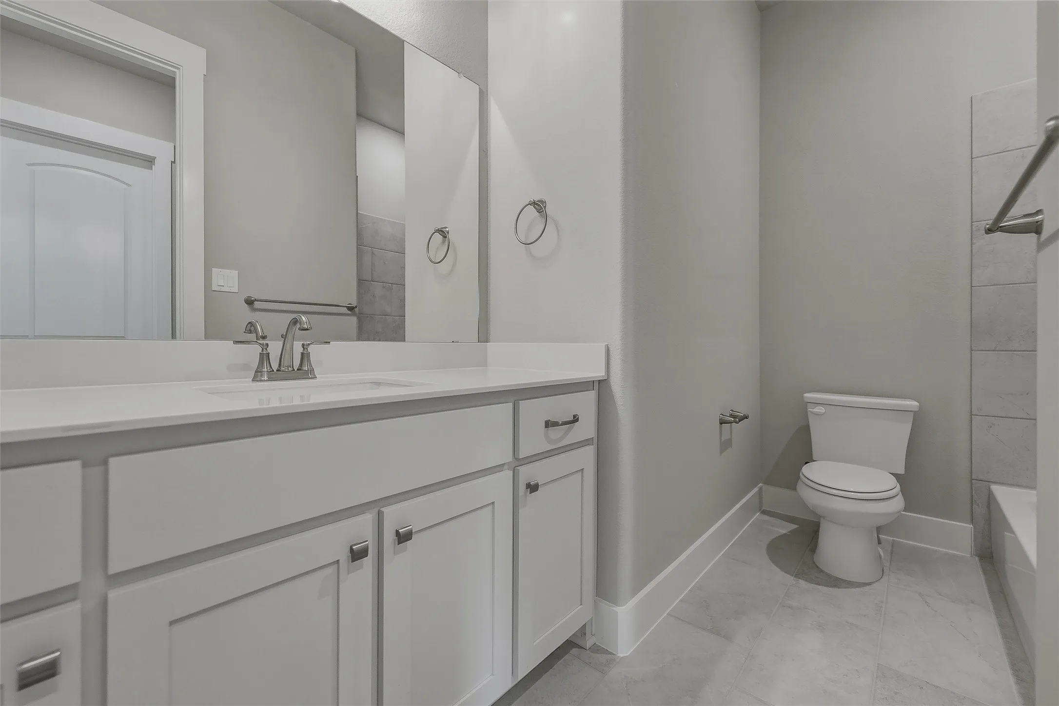 White shaker-style vanity with a light-toned countertop, undermount sink, and polished chrome faucet
