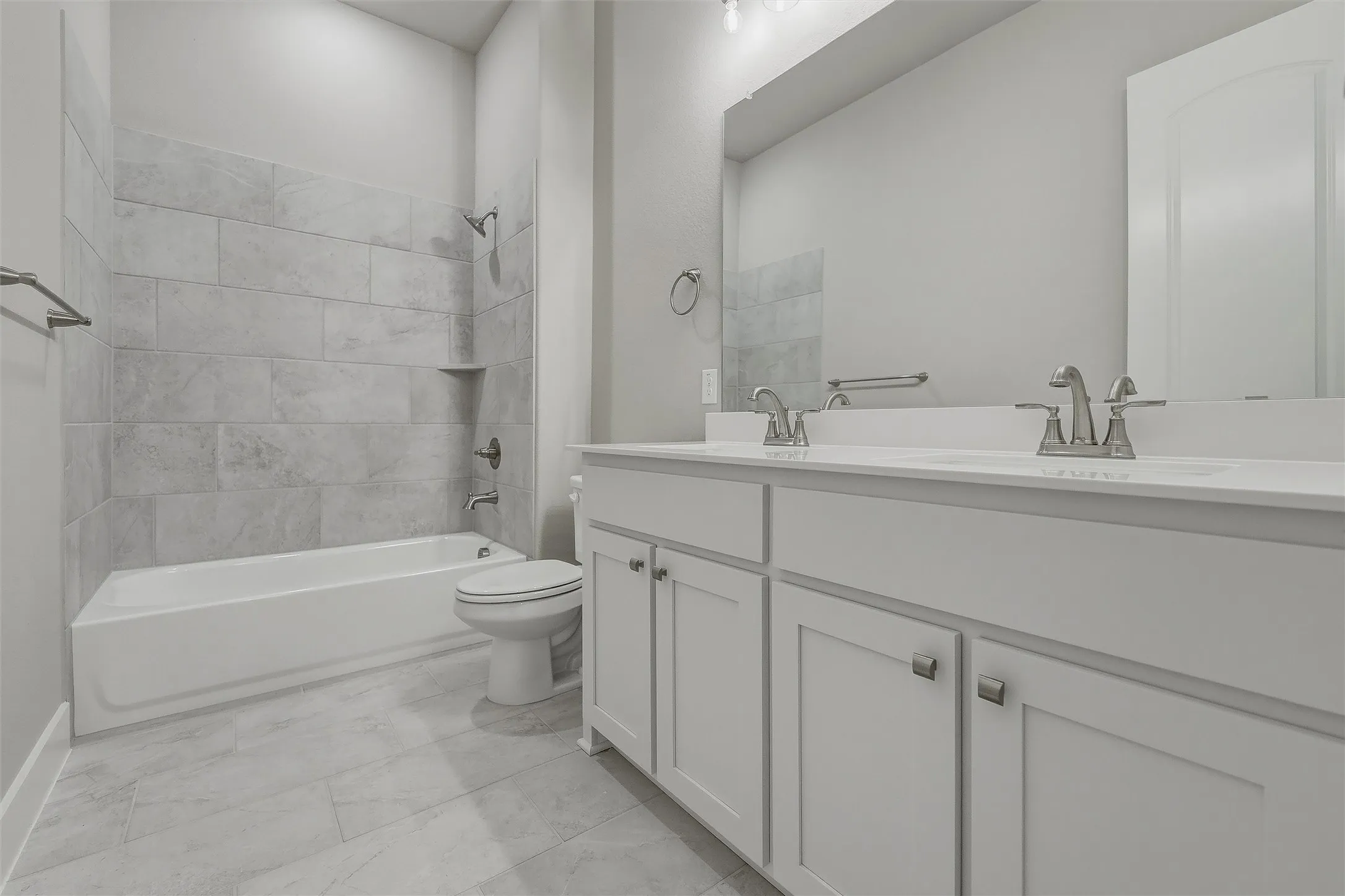 Dual vanity with white cabinetry, tile flooring, and a tiled tub/shower combination