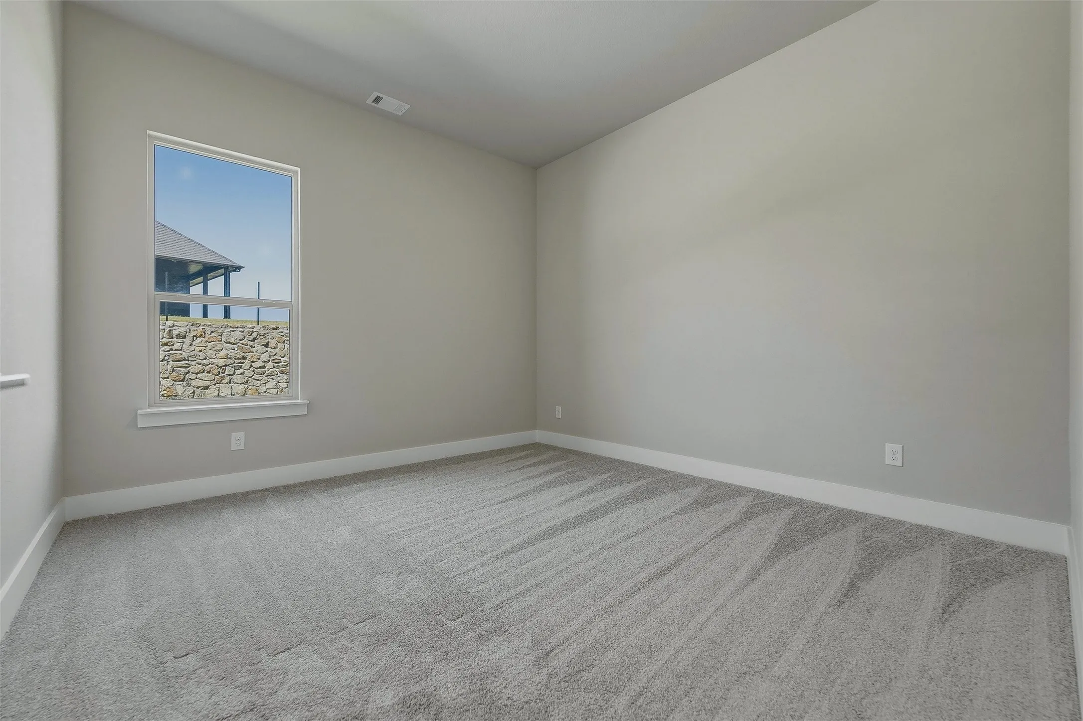 Gray patterned carpeting, white trim, and a window with a white frame