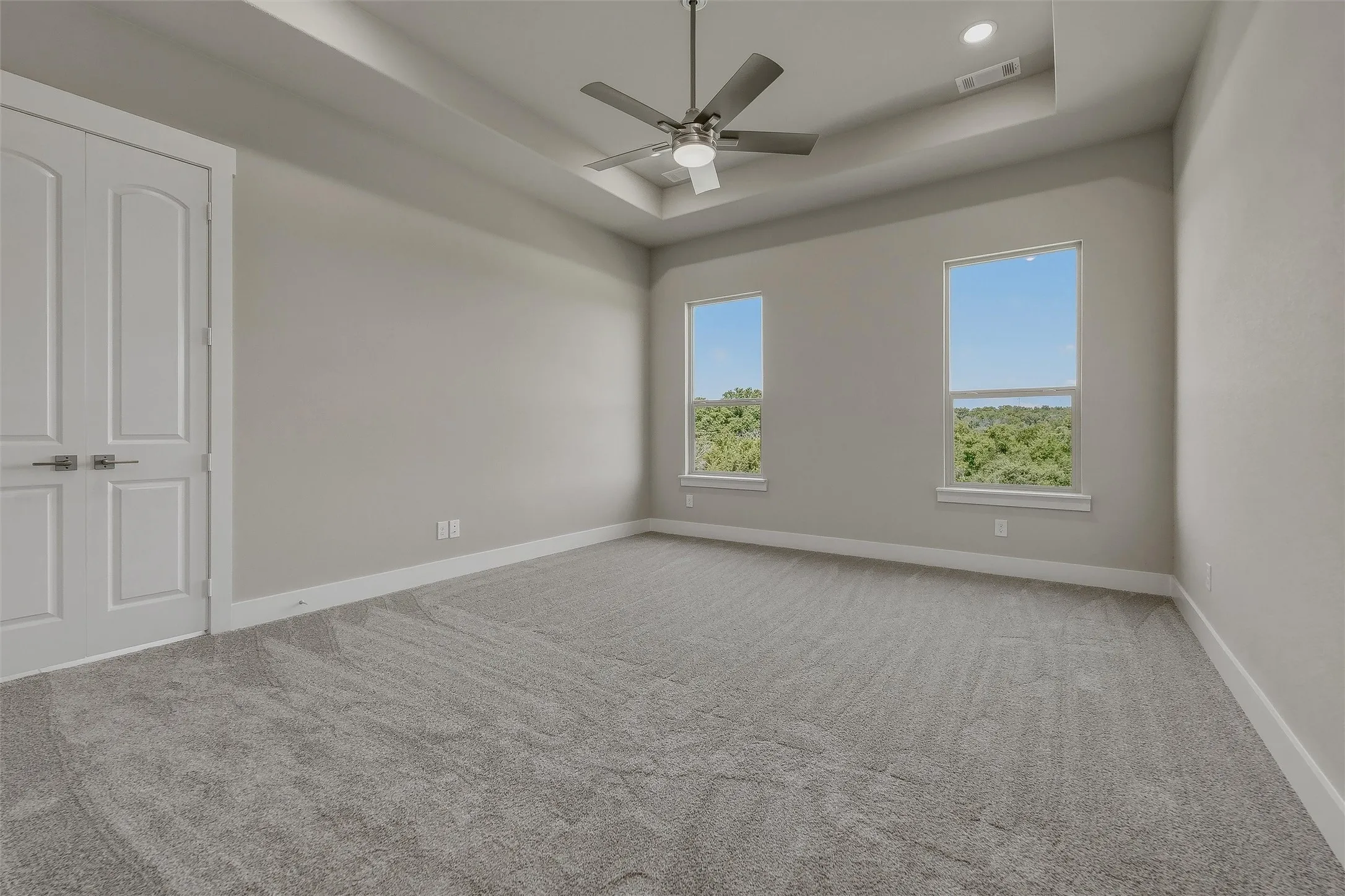 Tray ceiling with recessed lighting, ceiling fan, and light gray wall paint