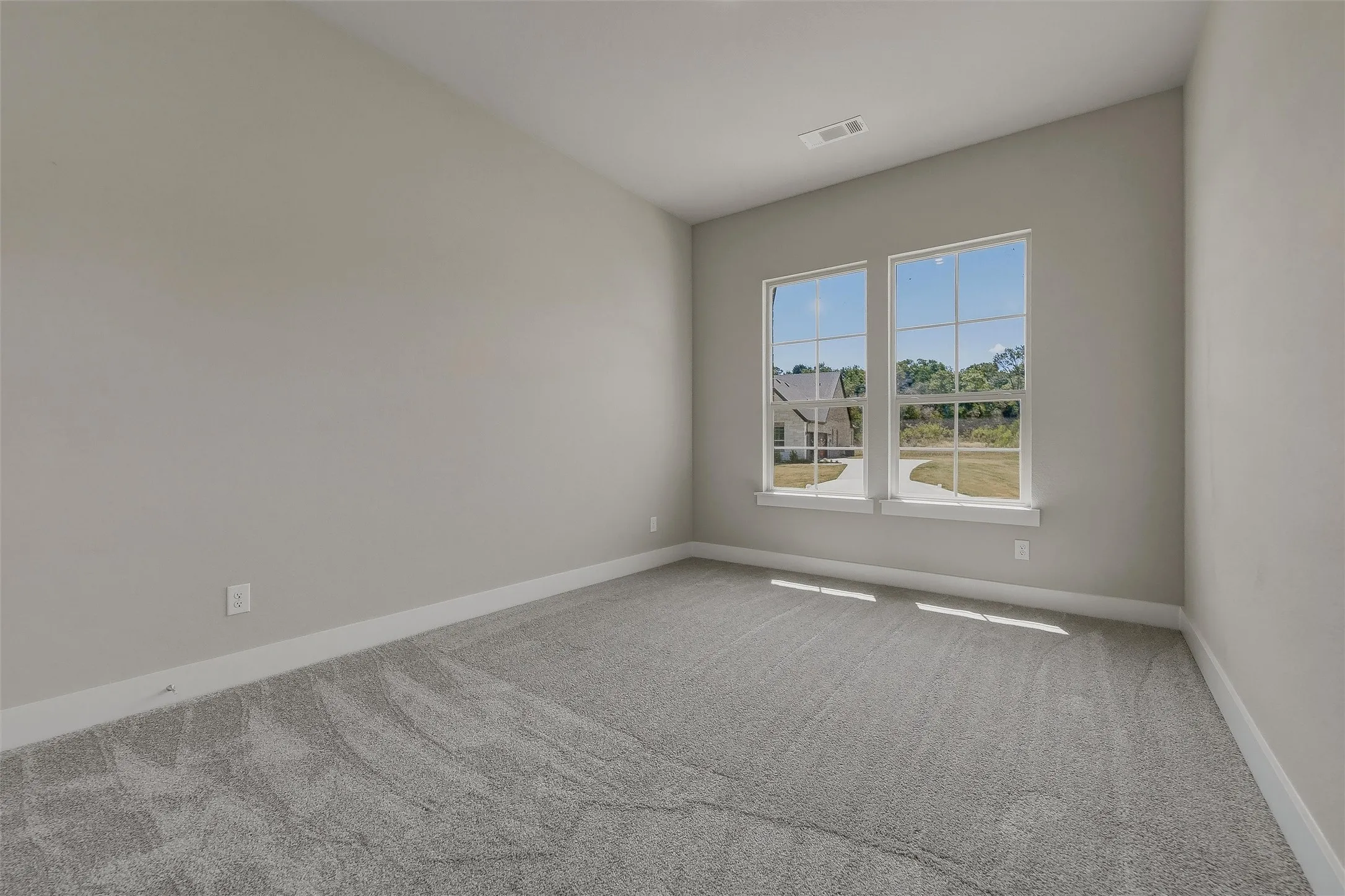 Neutral gray wall paint, gray carpeting, dual windows with white trim, and white baseboards
