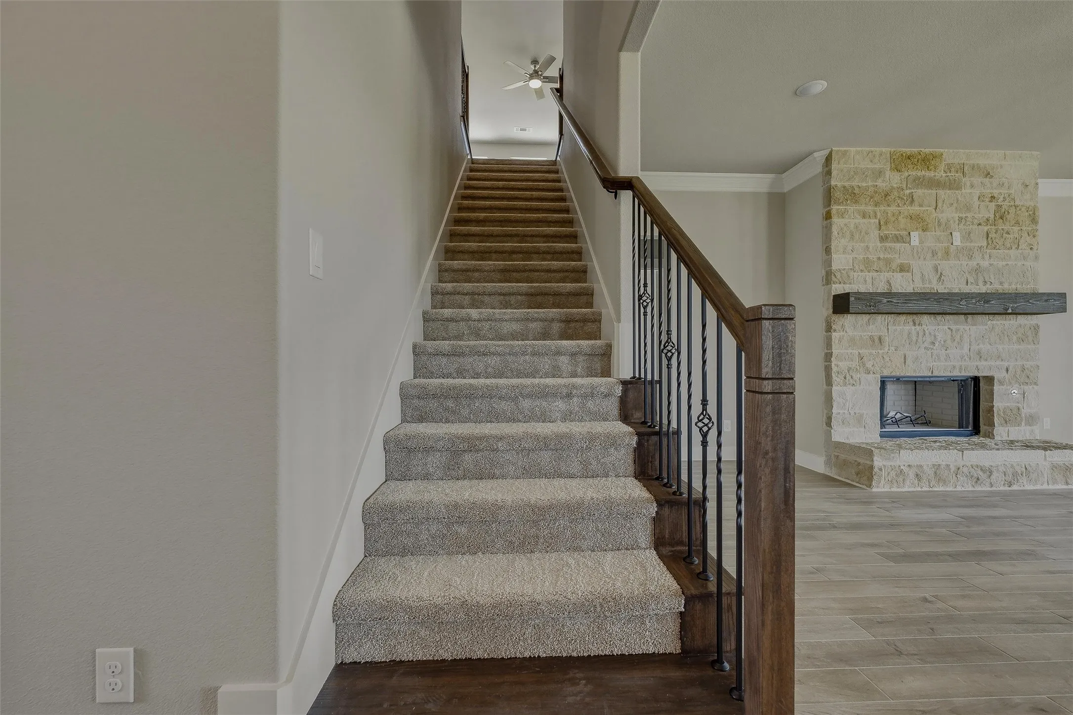 Carpeted staircase with wrought iron balusters and wood newel posts