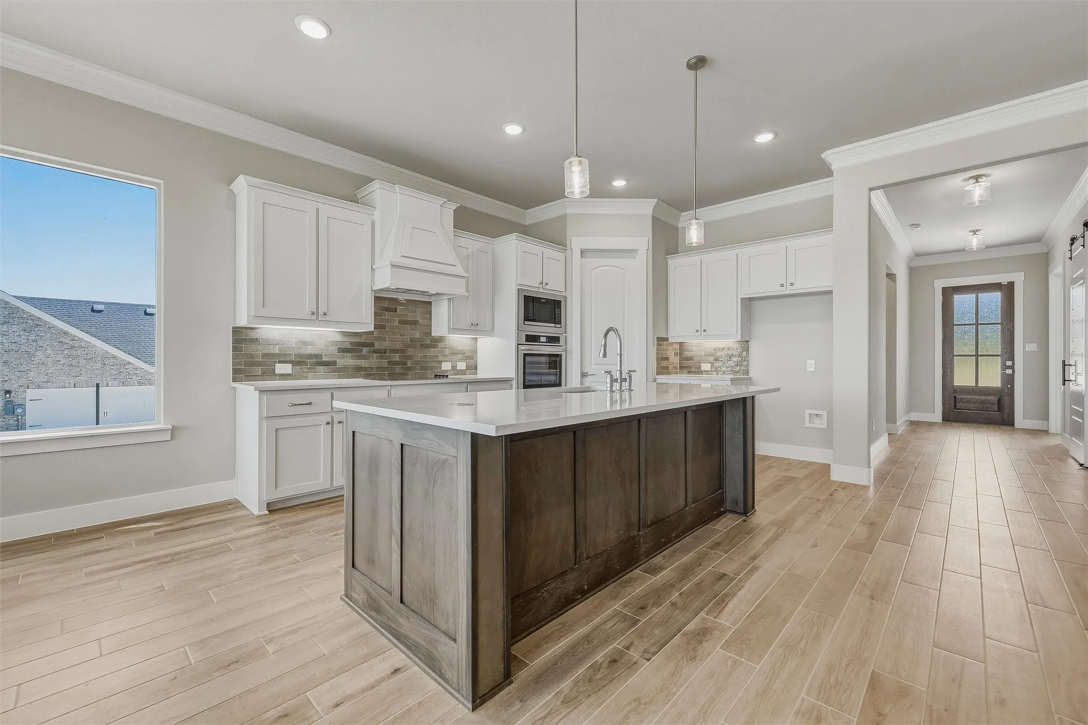 Kitchen with white cabinetry, a wood-finish island, built-in double ovens, and tile flooring