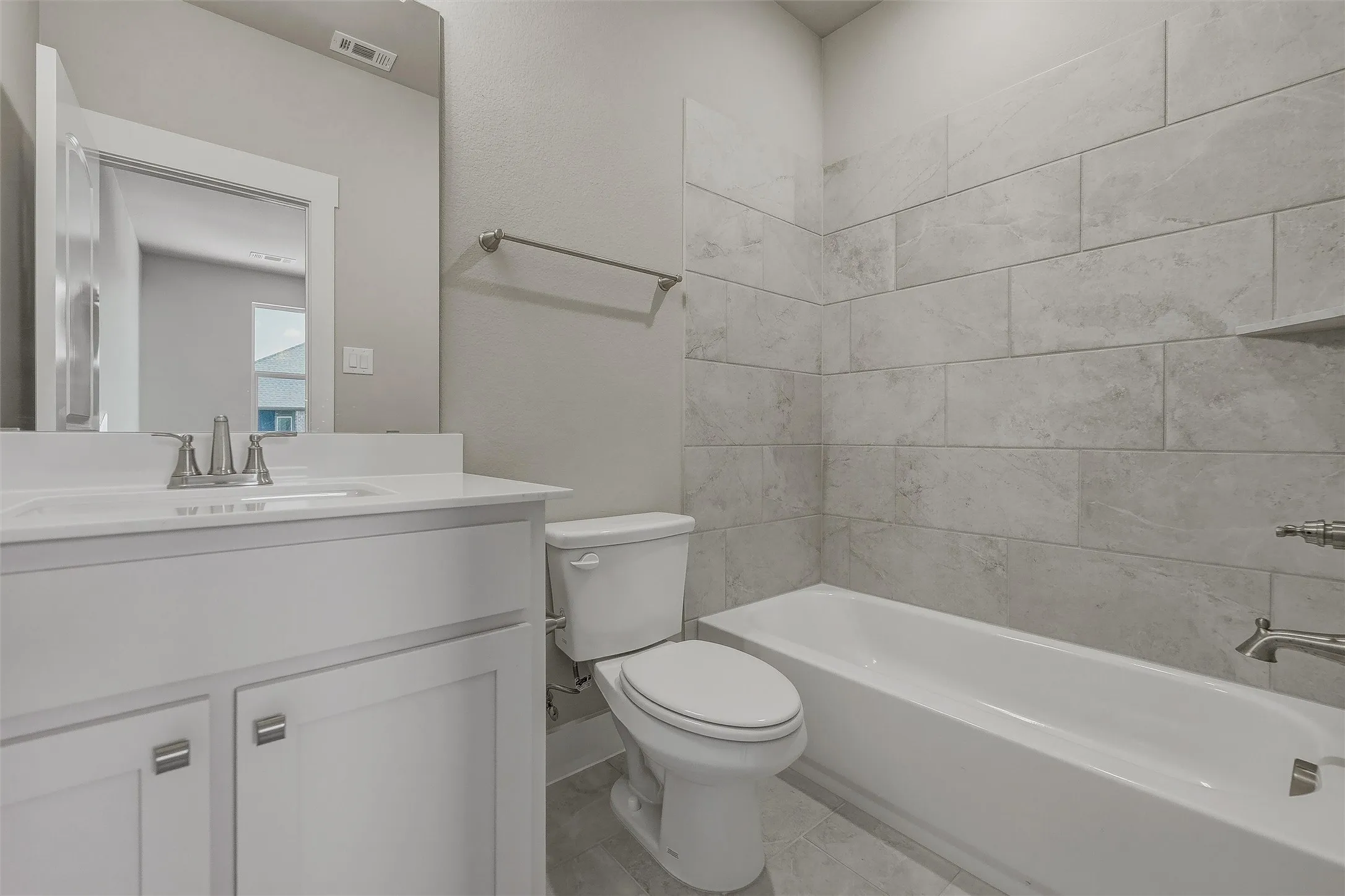 White vanity with brushed nickel hardware, integrated rectangular sink, wall-mounted mirror, and tile flooring