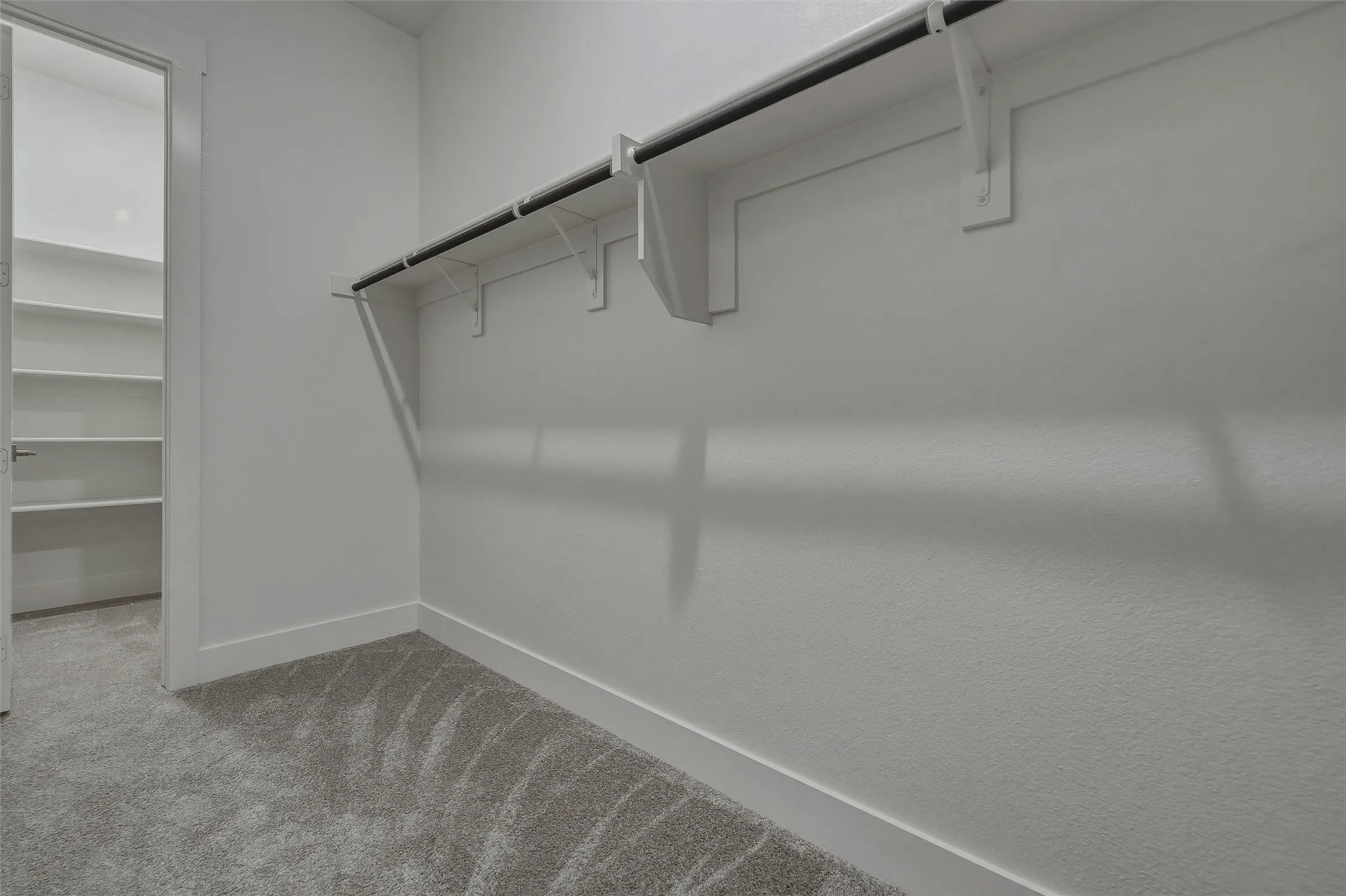 Carpeted walk-in closet with integrated shelving and hanging rods