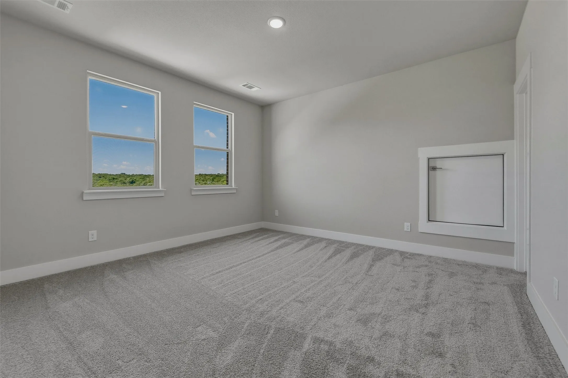 Room featuring neutral-toned carpeting, two windows, vaulted ceiling, and recessed lighting