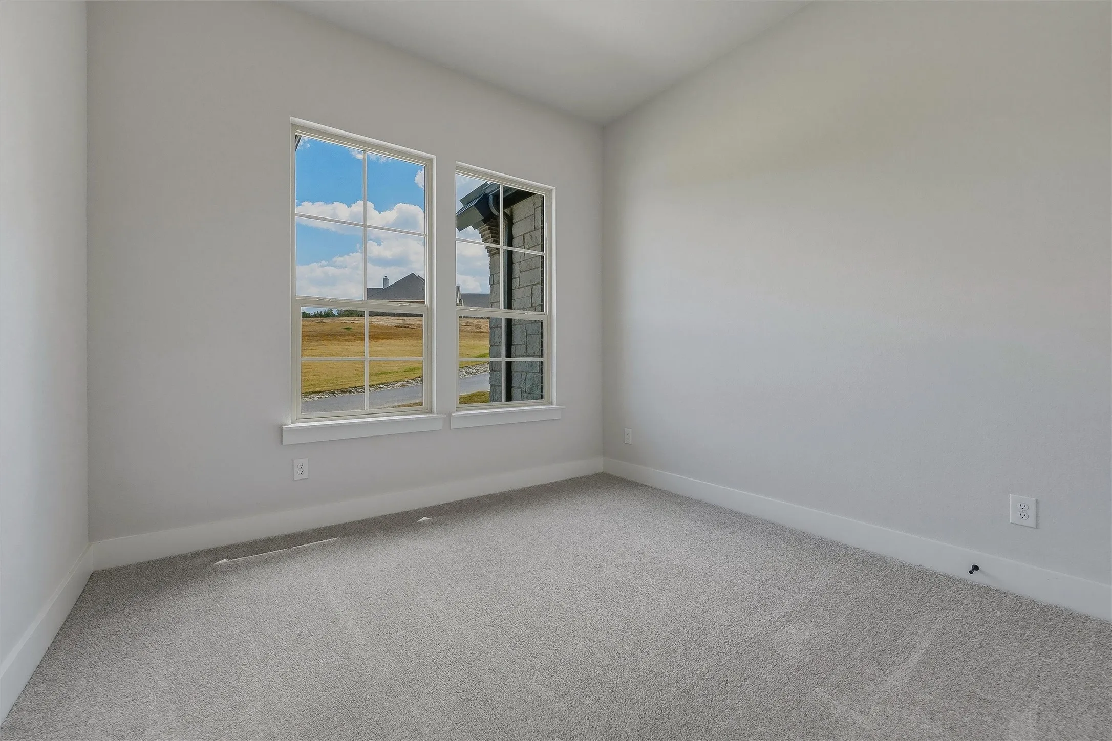 Vaulted ceiling with light gray walls, two paneled windows, and gray carpeting