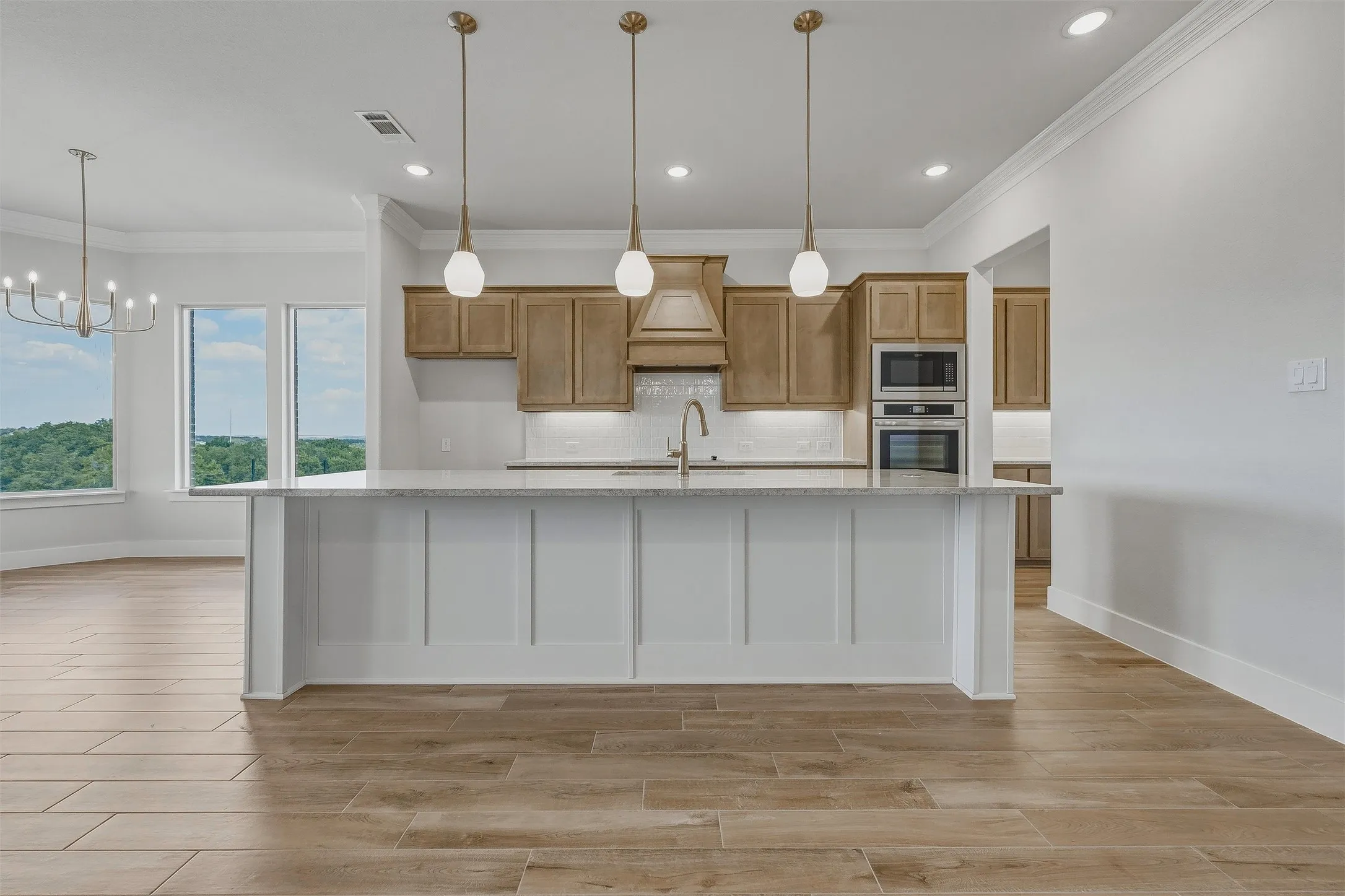 Gourmet kitchen with light wood-finish cabinetry, built-in stainless steel appliances, and a central island with a light-toned countertop