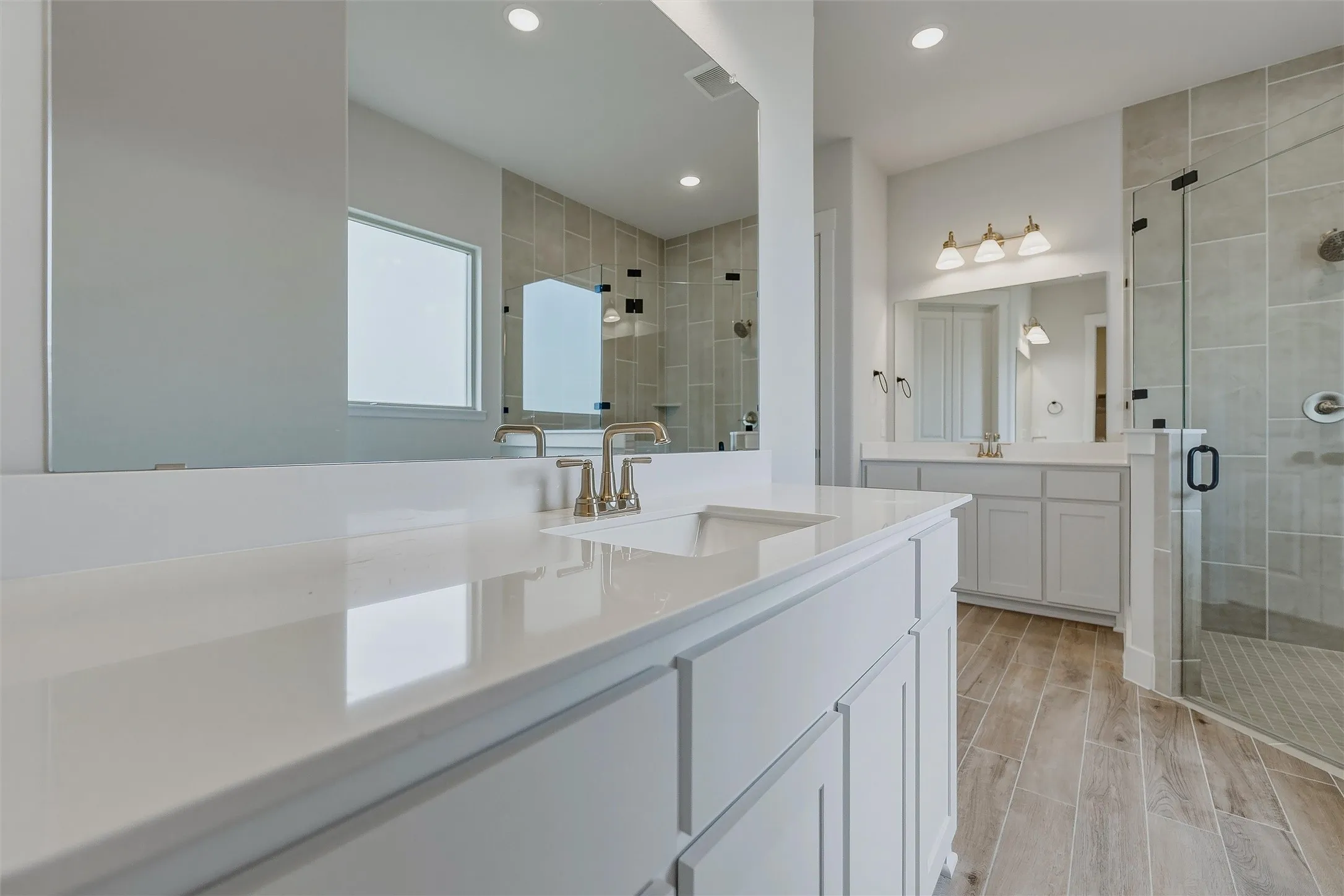 Dual vanities with white cabinetry, integrated sinks, and polished chrome fixtures